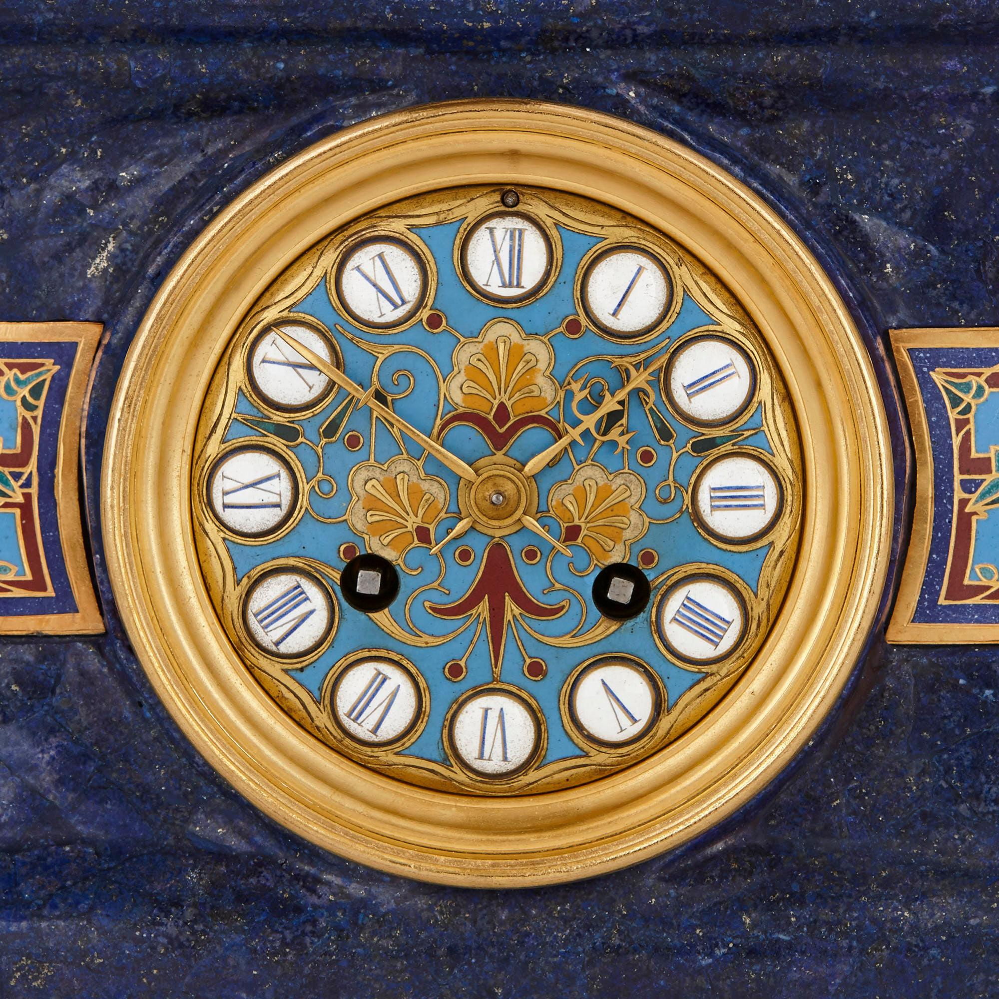 Inspirée par l'art et la culture de la Grèce classique, cette garniture de trois pièces contient une horloge de cheminée et deux candélabres. Le corps rectangulaire de l'horloge est en lapis-lazuli et est surmonté d'un vase grec, également en lapis.