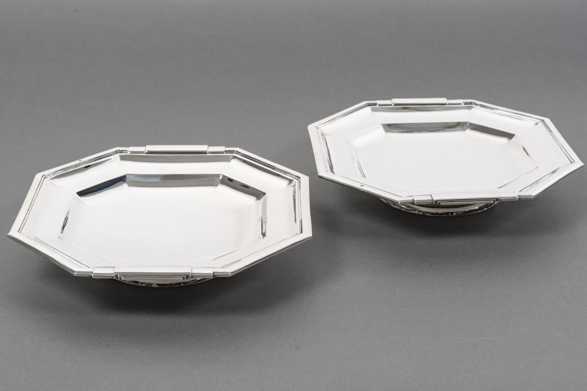 Paire de bols hexagonaux en argent massif, montés sur un piédestal rond, semi-creusés sur deux bords en forme d'ogive, les bords plats et les poignées de forme constructiviste sont représentés par deux demi-ronds qui se chevauchent. Ces pièces sont