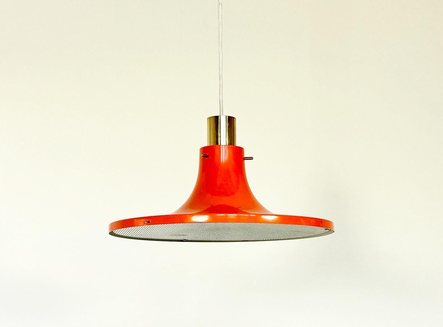 Lampe suspendue rouge-orange laquée des années 1960, conçue par Hans-Agne Agnes. 

Fabriqué en Suède par AB Markaryd, avec l'emblème du fabricant sur la face intérieure de l'écu. 

Rare lampe suspendue conçue par Hans-Agne Agnes en laiton et métal
