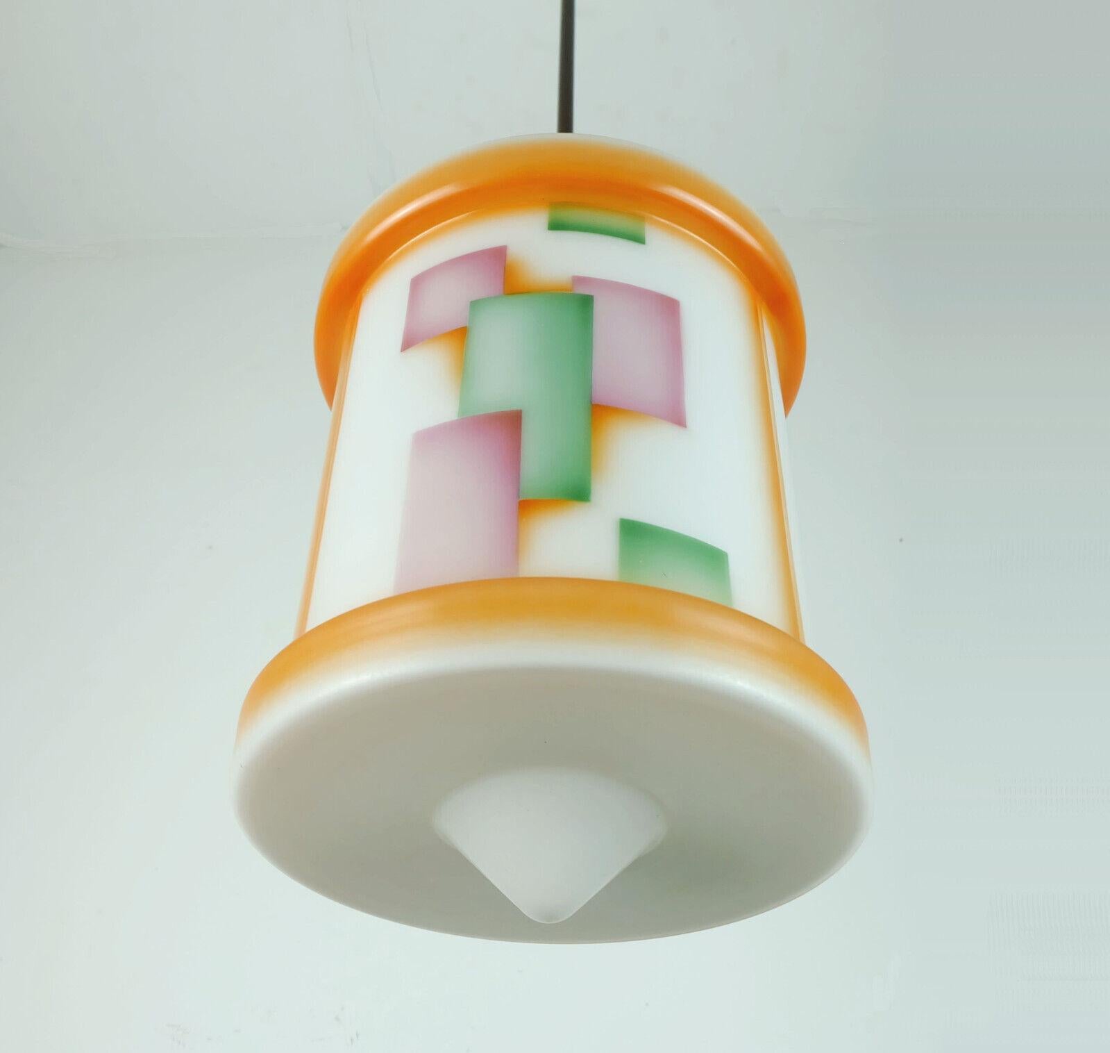 Very beautiful 1920s to 1930s hanging lamp. White satin glass shade with typical art déco shape and geometric air brush decor (so-called 'Spritzdekor') in orange, green and purple. Canopy, pole and top of the shade made of brown lacquered metal. For
