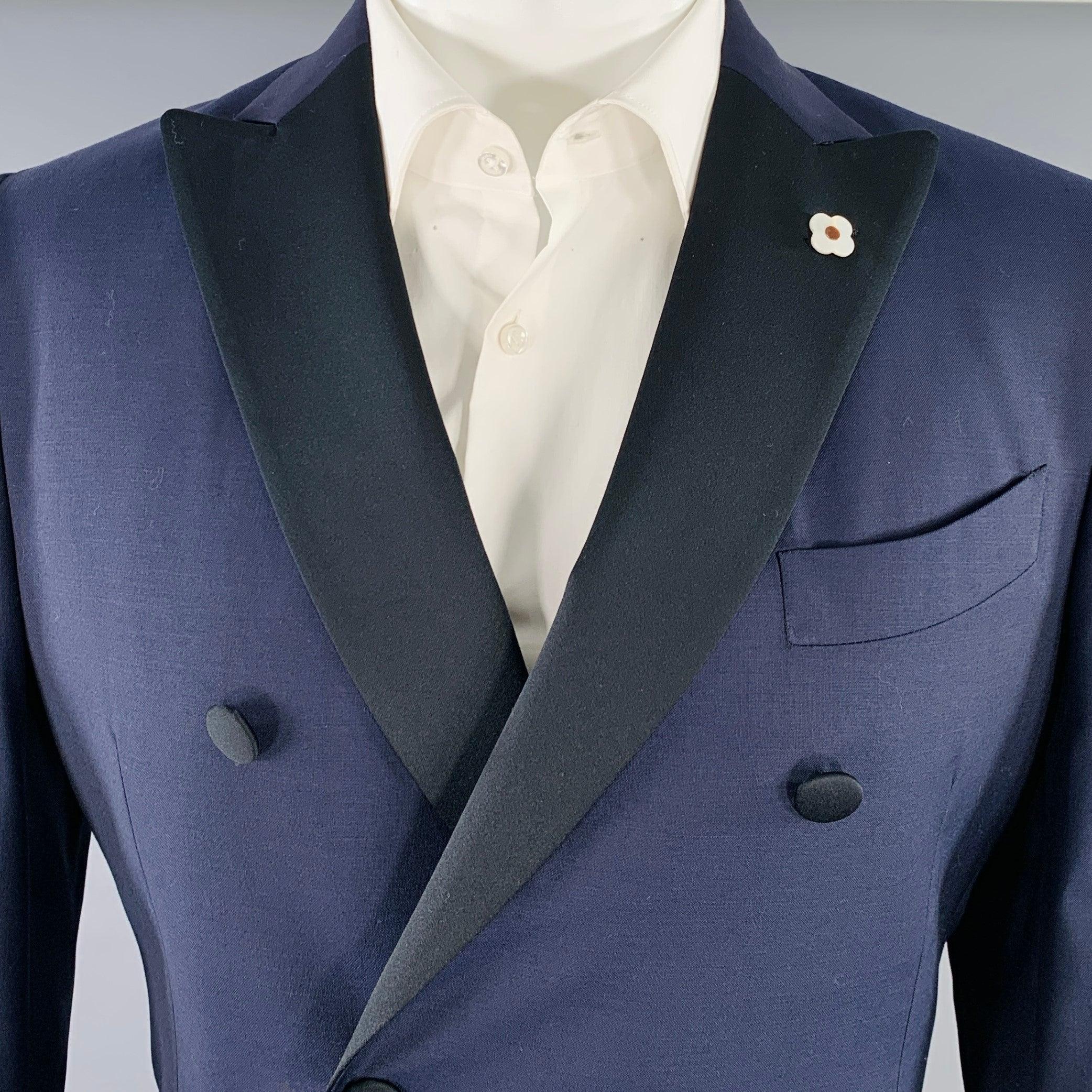 Smoking Lardini
en laine marine avec une doublure complète et comprend un manteau de sport à double boutonnage avec revers noir à visière (avec accent de boutonnière marguerite blanche) et un pantalon à devant plat assorti. Fabriqué en Italie.