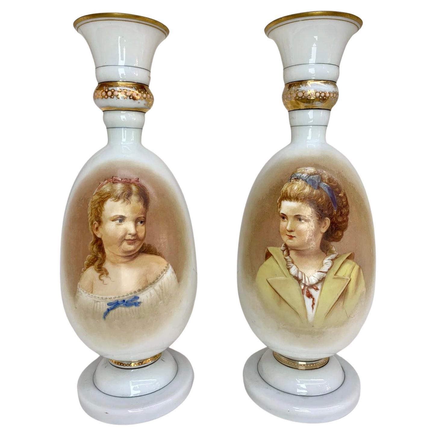A pair of 19th Century Victorian milky white opaline glass vases with gilding highlights and hand-painted portraits

The vases feature high-quality royal portraits of two young girls looking at one another

Height 39 cm.