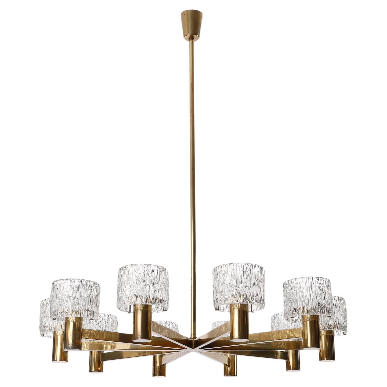 A beautiful and large 10-armed light fixture by J.T. Kalmar, Austria, manufactured in Mid-Century, circa 1960 (late 1950s to early 1960s). 
It consists of a frame made of solid, polished brass with an aged finish in a rich and warm tone with a great