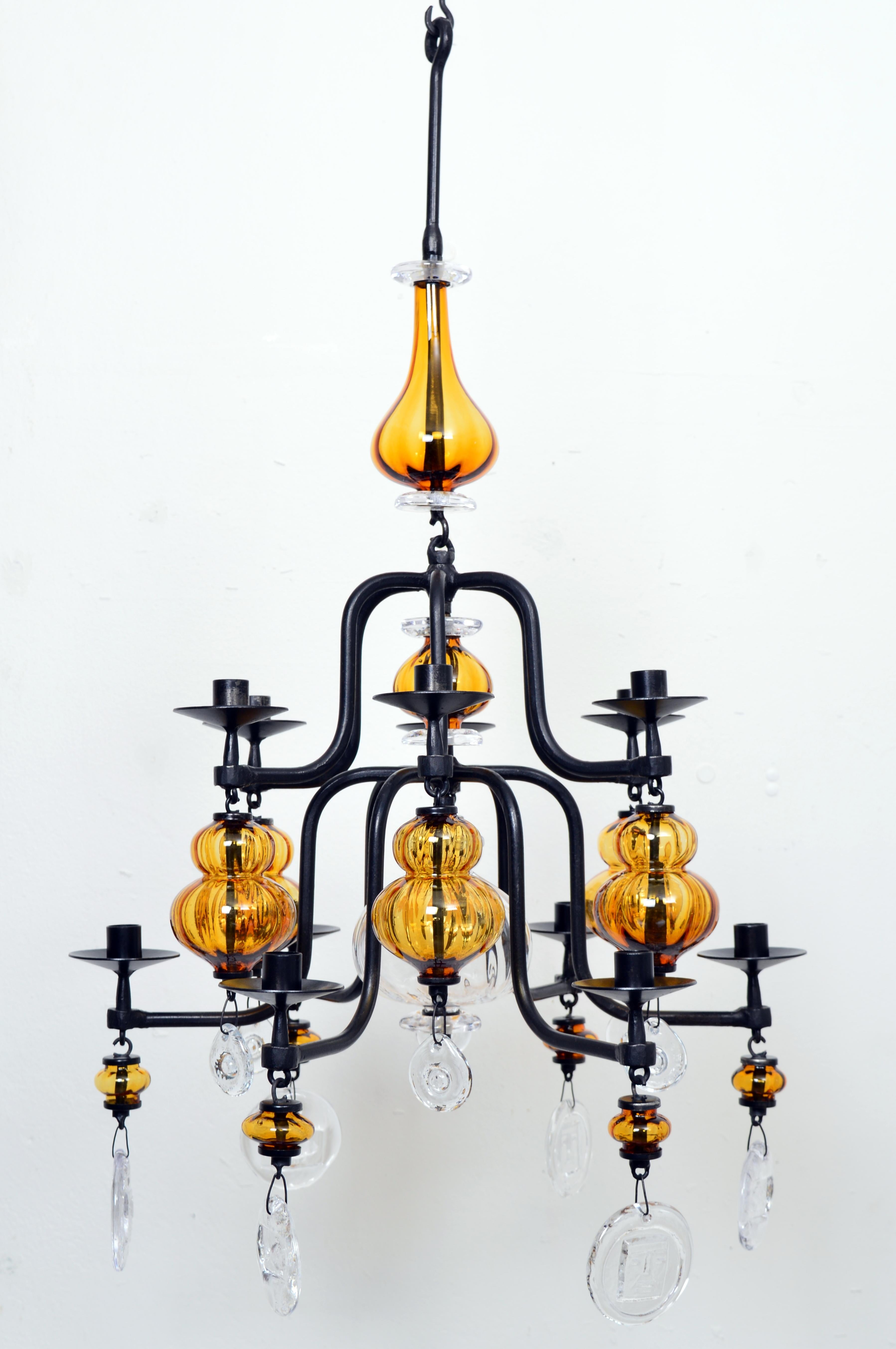 Esta hermosa lámpara candelabro de hierro forjado sobre vidrio artístico ámbar y transparente fue diseñada por Erik Höglund para Boda Smide. Erik Höglund (1932-1998) fue una de las estrellas más brillantes del diseño sueco en vidrio del siglo XX.