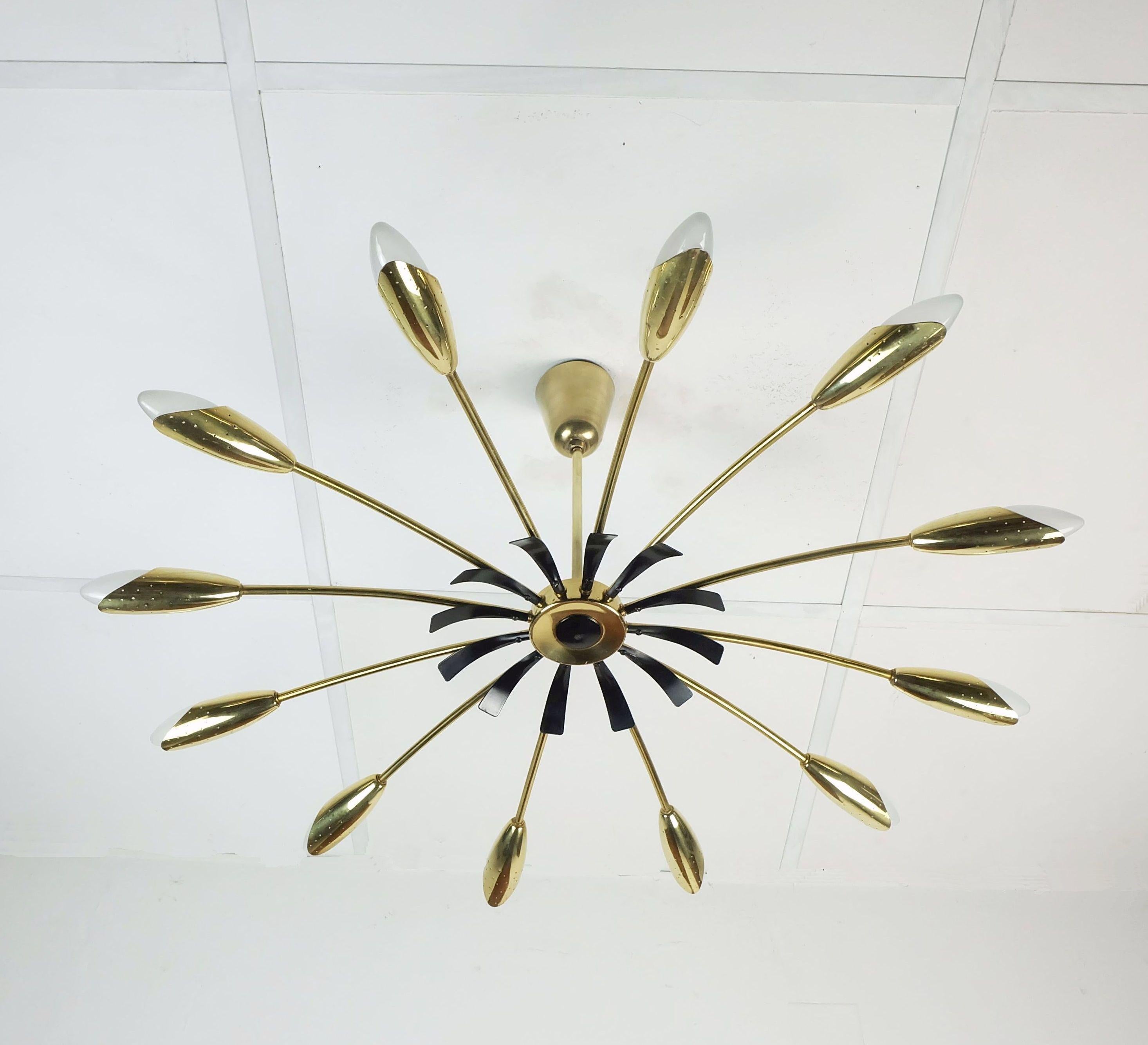 Una bellissima e grande lampada da soffitto Sputnik a 12 luci degli anni '50. Realizzato in ottone, con elementi decorativi in metallo laccato nero. Il motivo traforato delle prese crea un effetto luminoso particolarmente bello. Per lampadine a