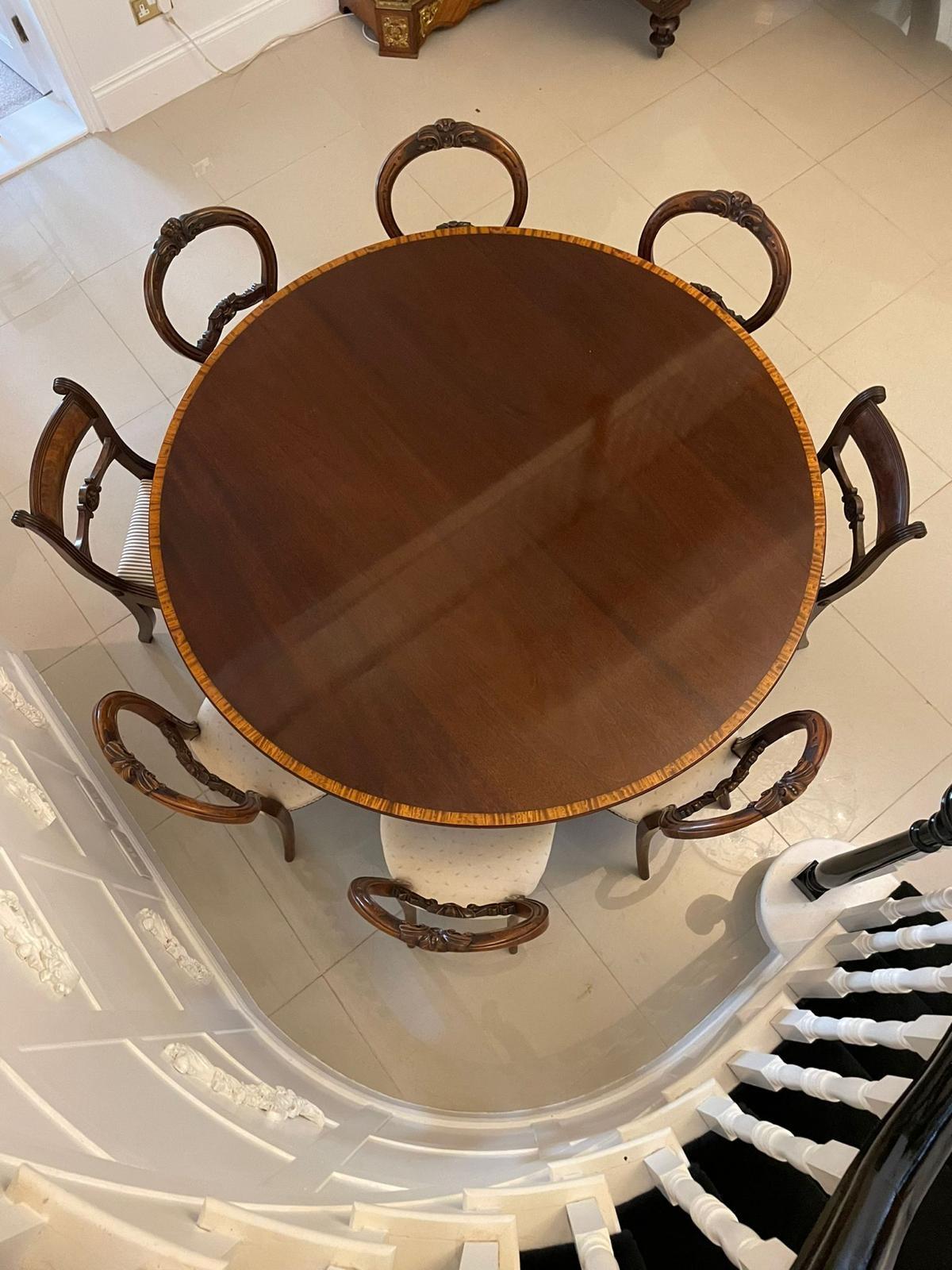 Large 12 seater antique mahogany extending dining table having a magnificent quality figured mahogany satinwood crossbanded circular top with a moulded edge, five extra leaves supported by square mahogany columns, shaped mahogany platform base
