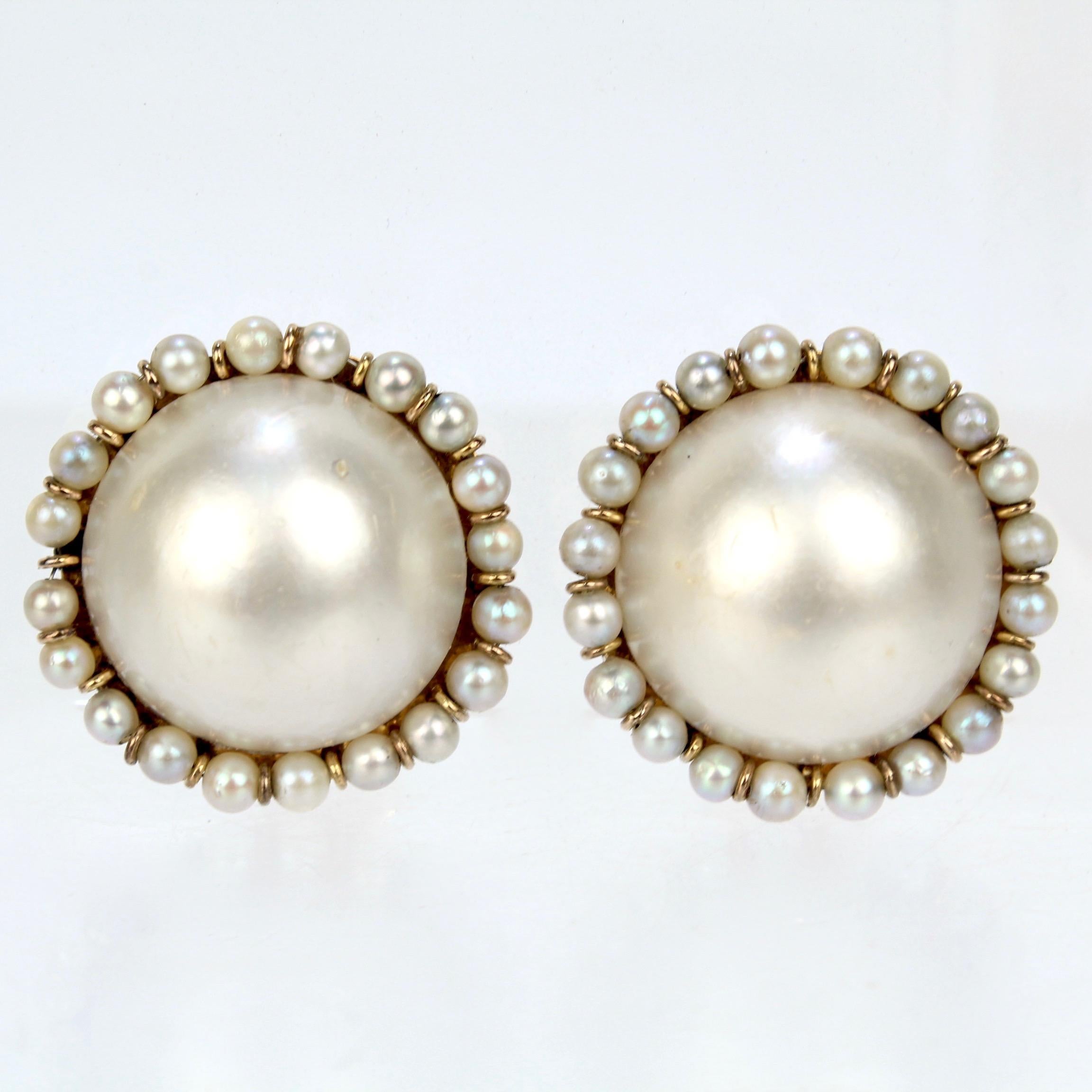 A wonderful pair of gold and mabe pearl earrings.

With large mabe pearls center set and framed by small round pearls on a 14k gold mount with a snowflake pattern to the reverse.

Th clips are marked 14K for gold fineness.

Simply a wonderful pair