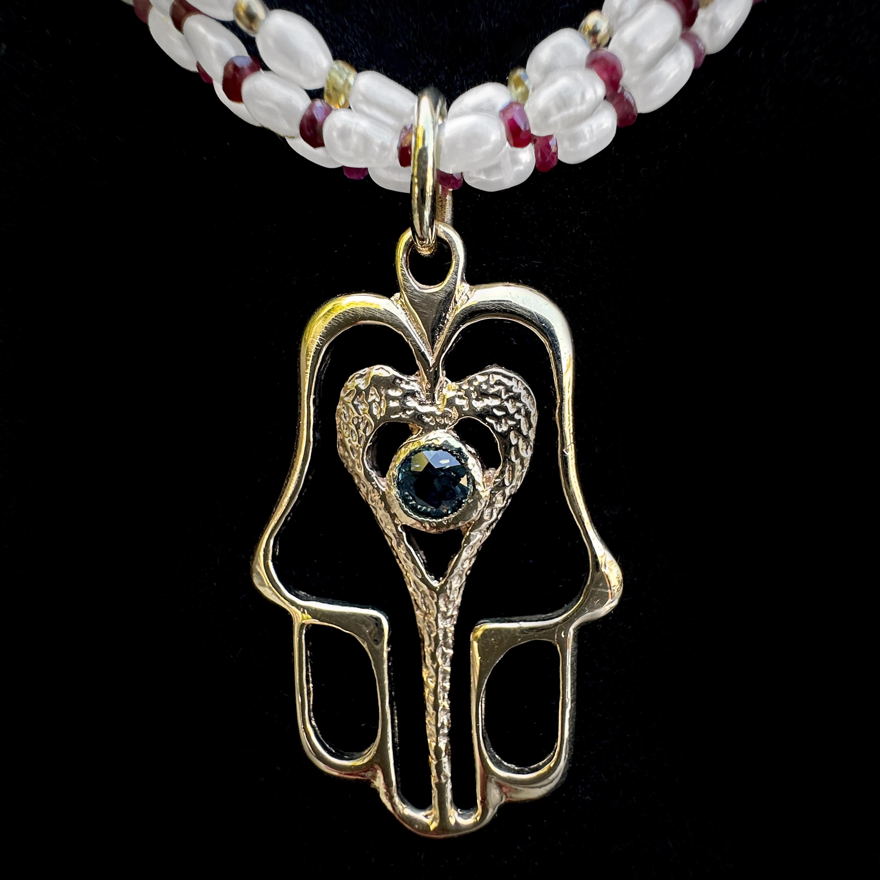 Questo grande ciondolo hamsa è in oro massiccio 14 carati e offre un sacco di simbolismi positivi - amore, amicizia o buona fortuna, a seconda di chi lo chiede - ma tutti giusti.  Presenta un cuore interno testurizzato con uno zaffiro blu brillante