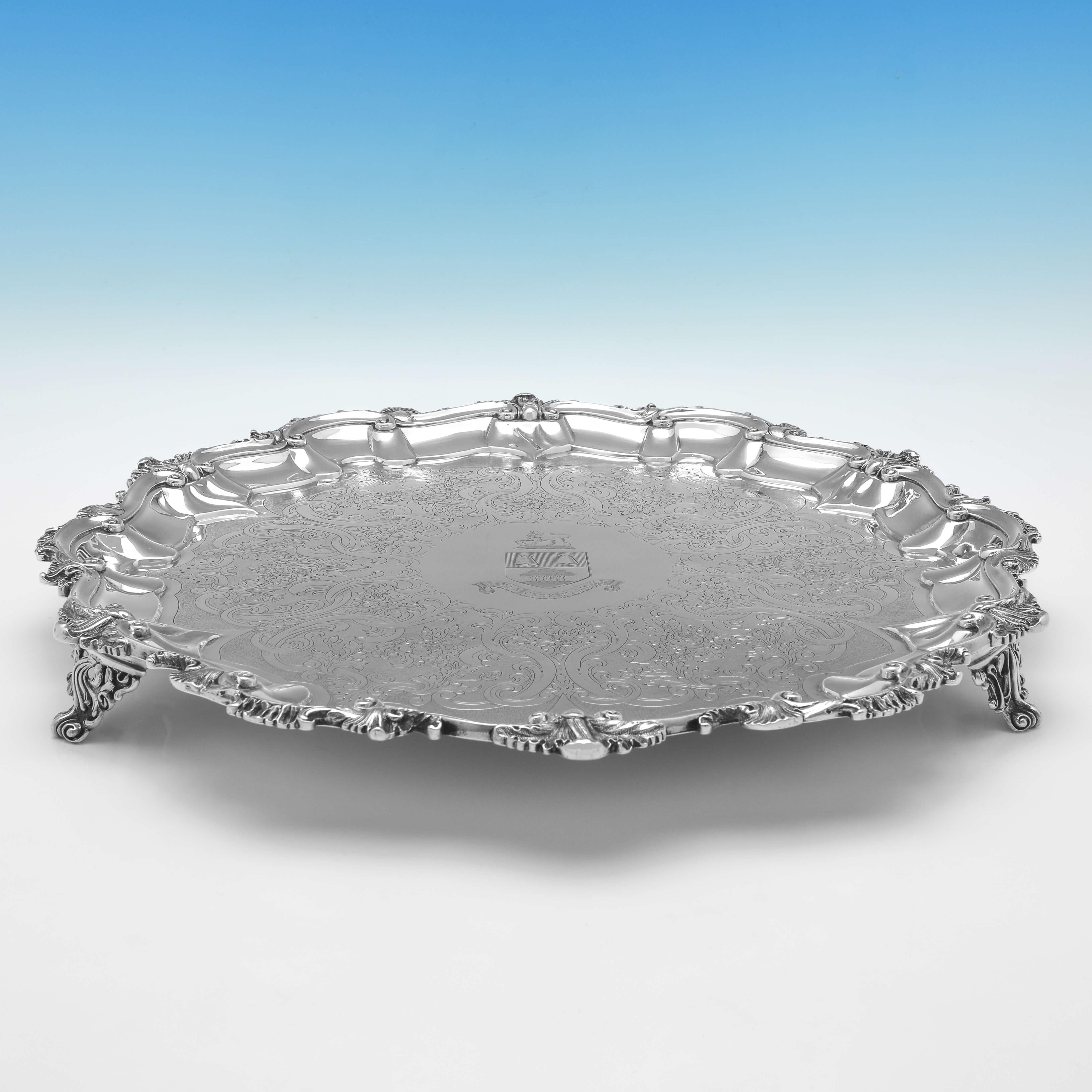 Hallmarked in Edinburgh in 1857 by J. Mckay, this attractive, Victorian, Antique Sterling Silver Salver, has a shell and scroll border, engraved decoration, and an engraved coat of arms to the centre. 

The salver measures 17.25