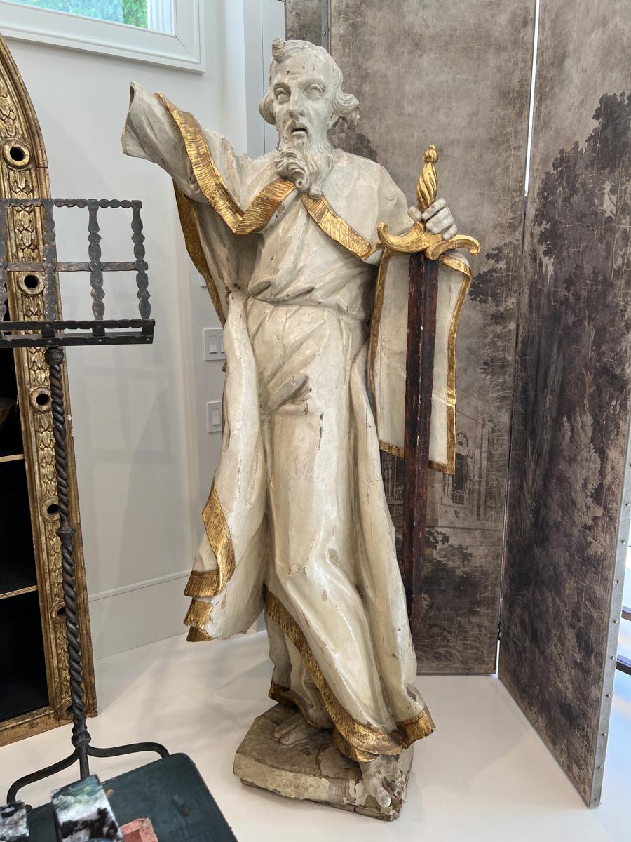 Over life size wooden sculpture of of St. Peter with a sword.  Gold trims his cloak.  