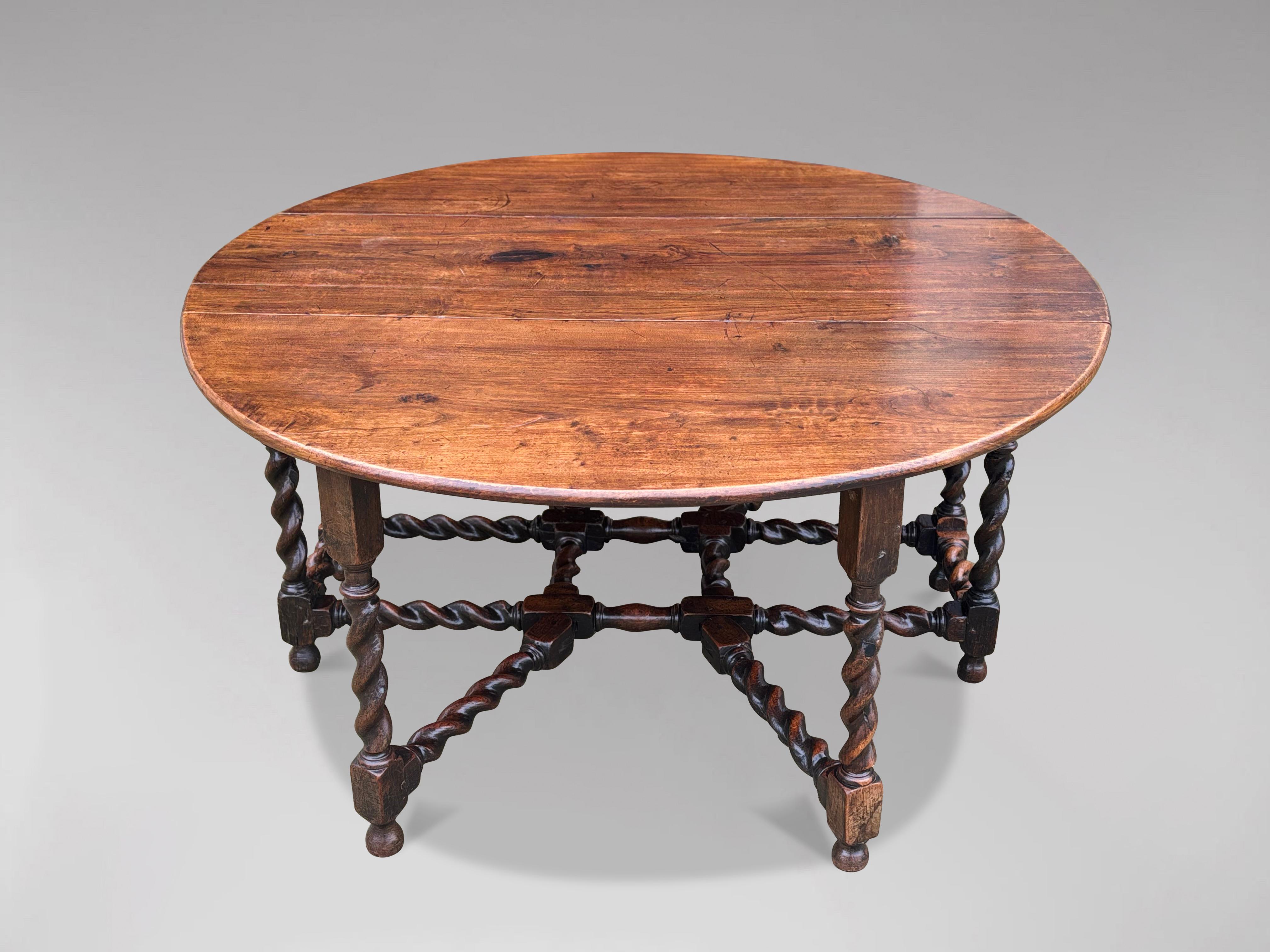 A stunning mid 17th century, Charles II period, large solid oak double gateleg dining table. The oval plank oak top above bold barley twist turned uprights with matching twin knuckle joined gates, joined by further twist turned stretchers and tie