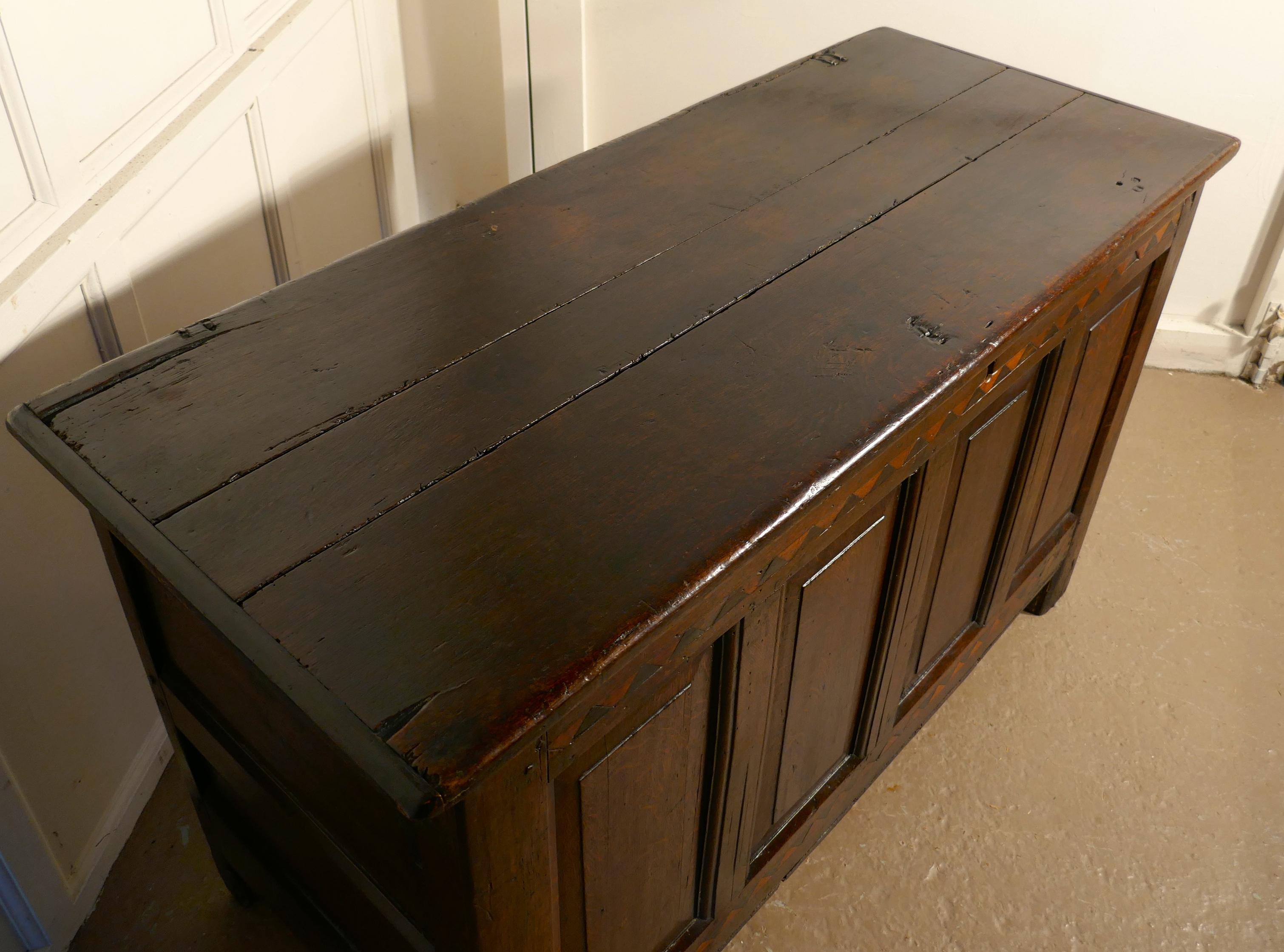 A large 17th century inlaid panelled oak coffer.

This is a lovely old piece, with a superb patina, the chest has three deep moulded panels on the front with a heavy oak plank top
The front also has a diamond inlaid border top and bottom, and it