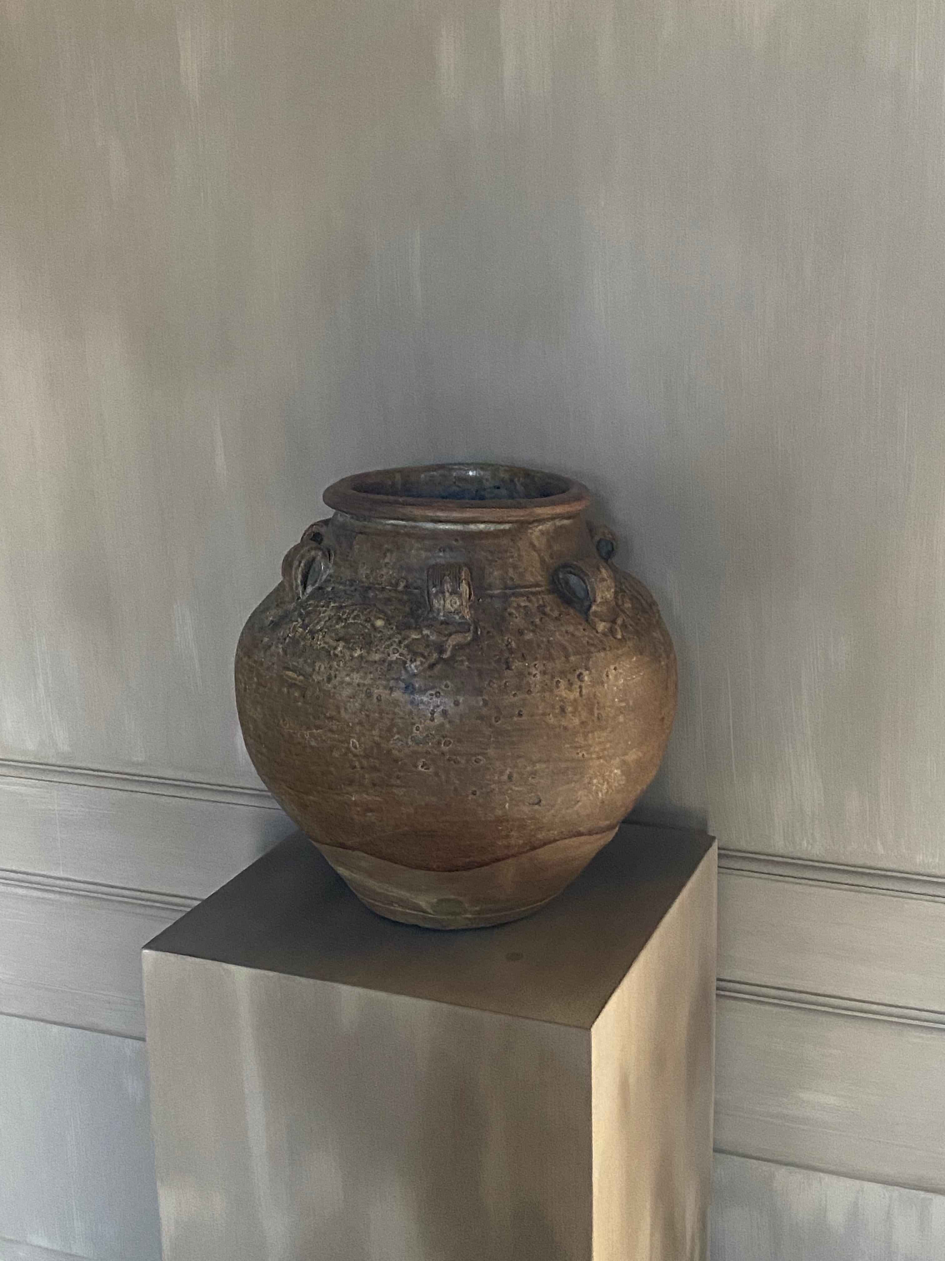 A large 17th Century Thai earthenware storage jar.
With a row of loop handles beneath the rim and relief modeled small dragons, covered in a roughish brown glaze, falling unevenly and well short of the foot. Old restoration, perfectly done.


Ask