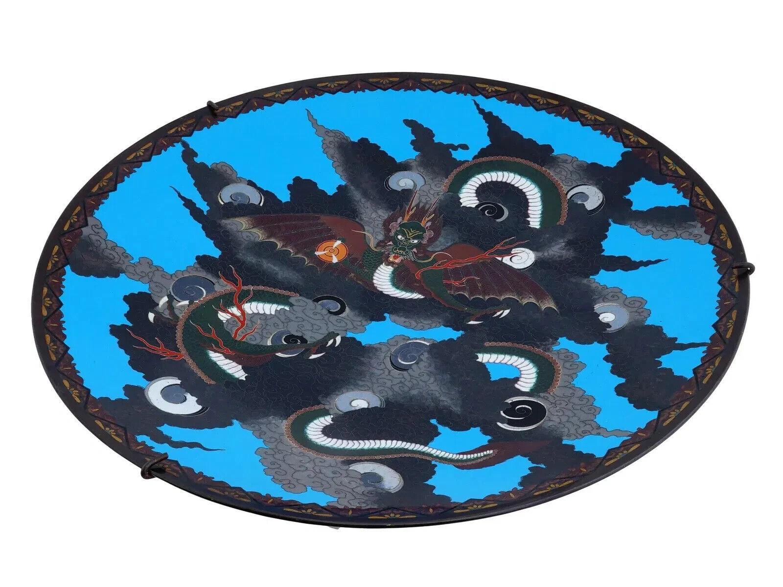 Antiguo plato japonés de esmalte cloisonné, con una representación central de un dragón sobre fondo azul y borde decorado. Alrededor del siglo XIX. Antiguos objetos de colección japoneses de esmalte y decoración para el hogar.

Dimensiones: D 18