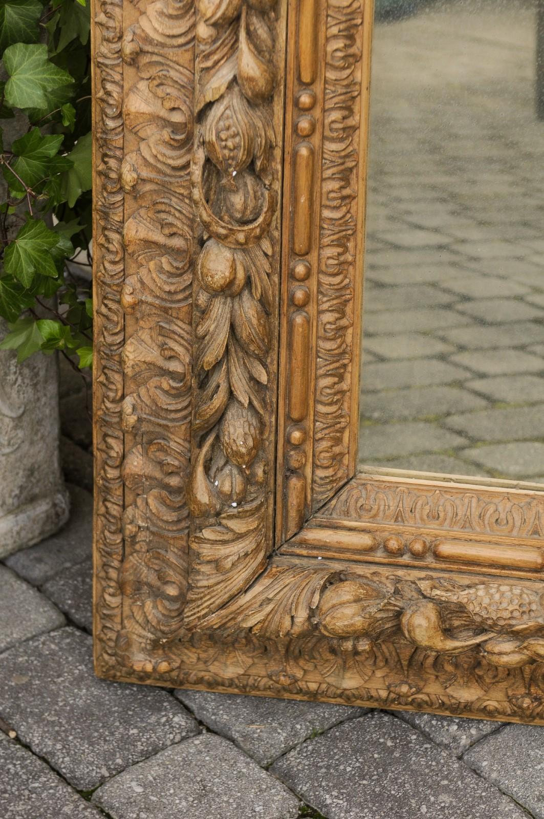 A French large size hand carved rectangular oak mirror with fruit and foliage motifs from the second half of the 19th century. Born in the third quarter of the 19th century, this French wooden mirror features an exquisitely carved rectangular frame,