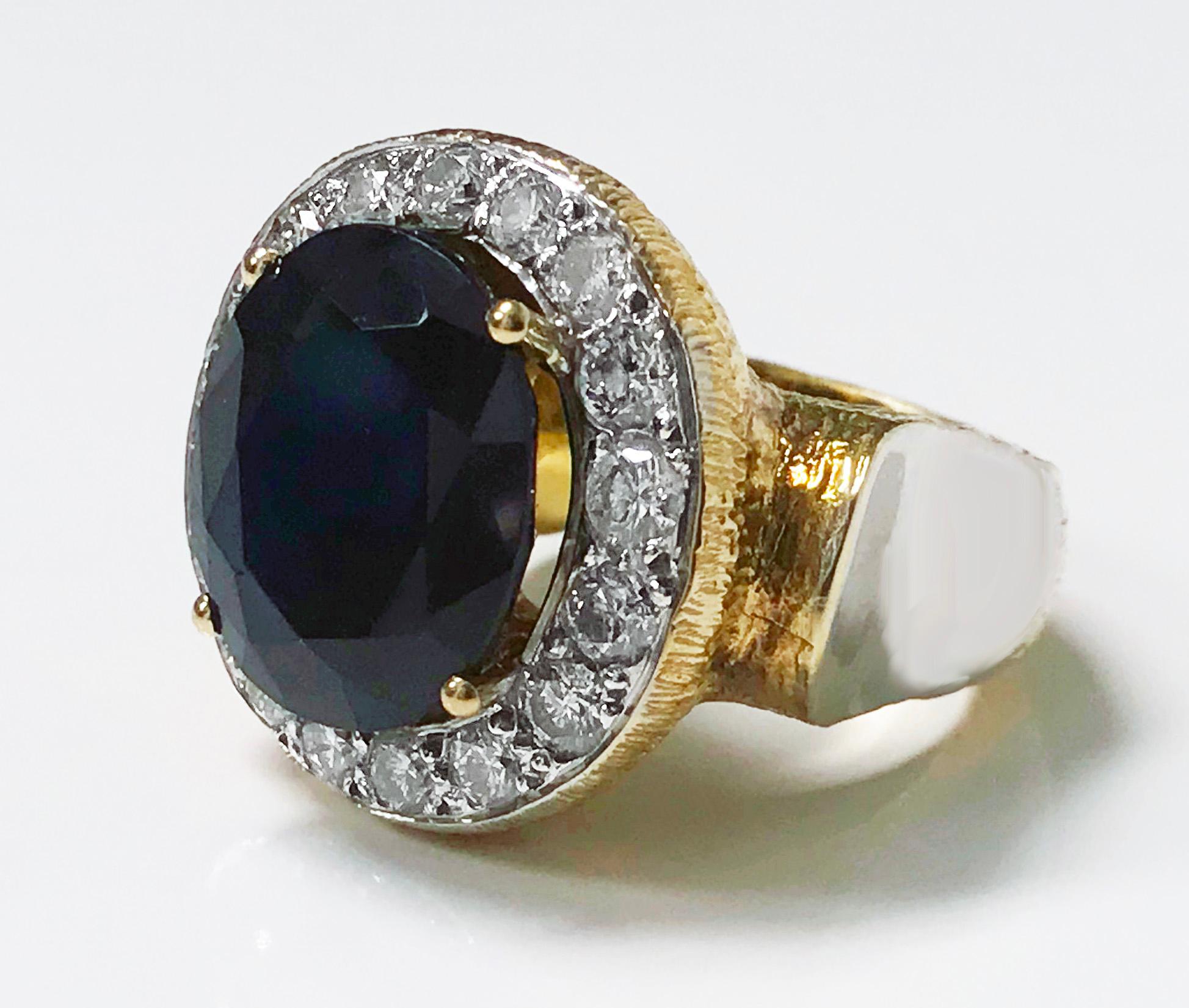 Large 18K Diamond and glass filled sapphire Ring. The ring claw set with a glass filled hybrid corundum semi-translucent sapphire, gauging approximately 16.00 x 13.90 x 8.00 mm, approximately 14.40 cts, with a surround of 16 round brilliant cut