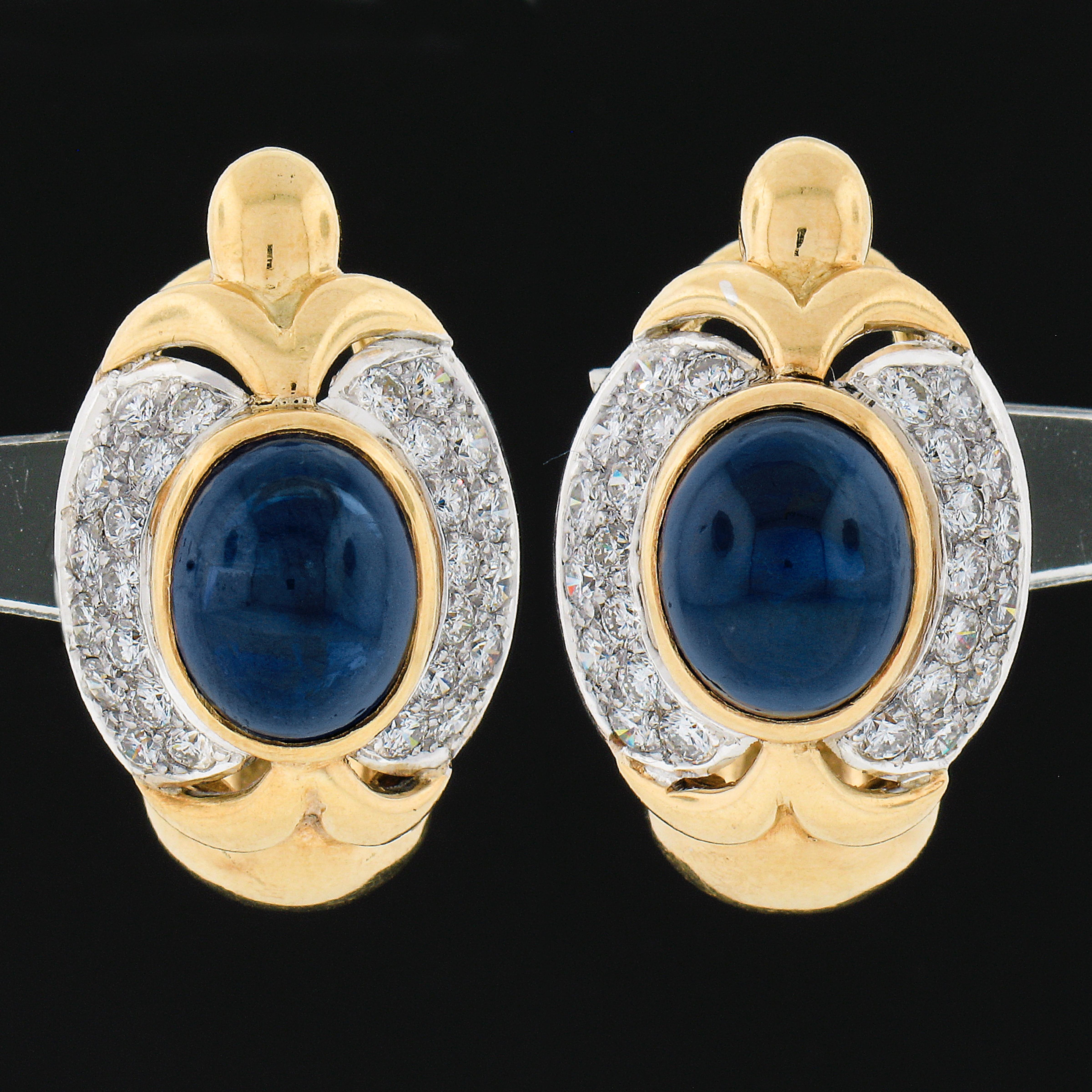 This magnificent pair of sapphire and diamond statement earrings was crafted from solid 18k yellow and white gold. The earrings feature a pair of beautiful, GIA certified, oval cabochon cut sapphires that are perfectly bezel set at the center of a