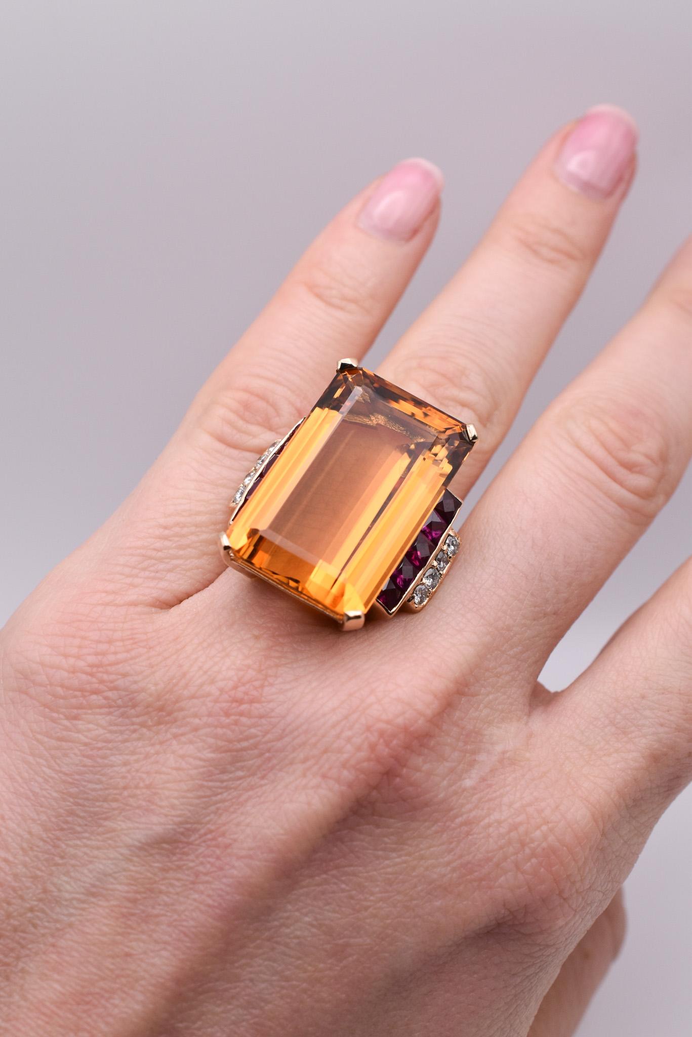 A Large Citrine Cocktail Ring in 18K Yellow Gold, showcasing an emerald-cut citrine weighing approximately 33.50 carats further embellished with Diamonds and Synthetic Ruby Accents. Made in America, circa 1950.