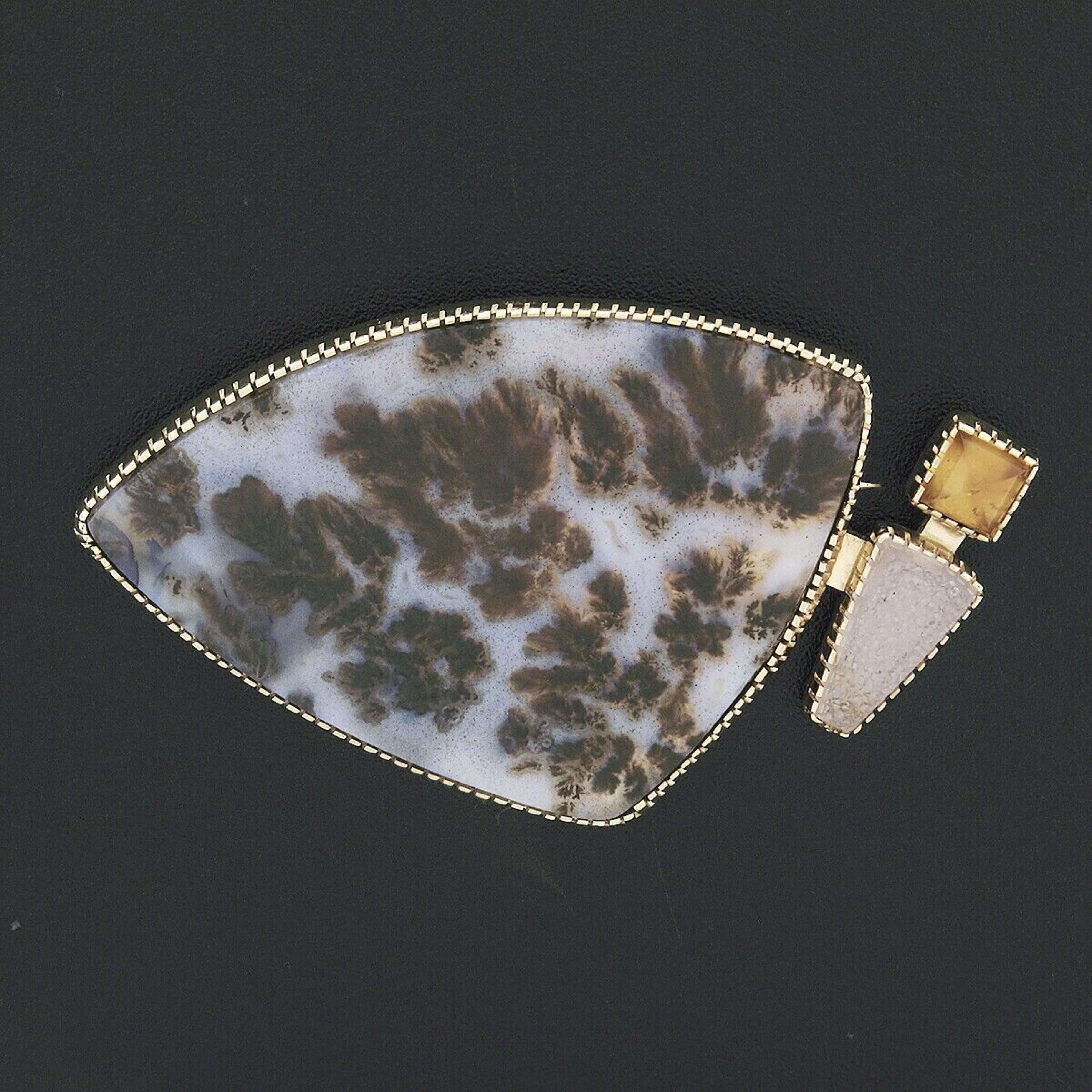 This large and unique designer brooch was crafted from solid 18k yellow gold. It features a large, flat top, free-form cut piece of natural agate accented on the side by two smaller stones. The agate has a bluish-white base color with large brown