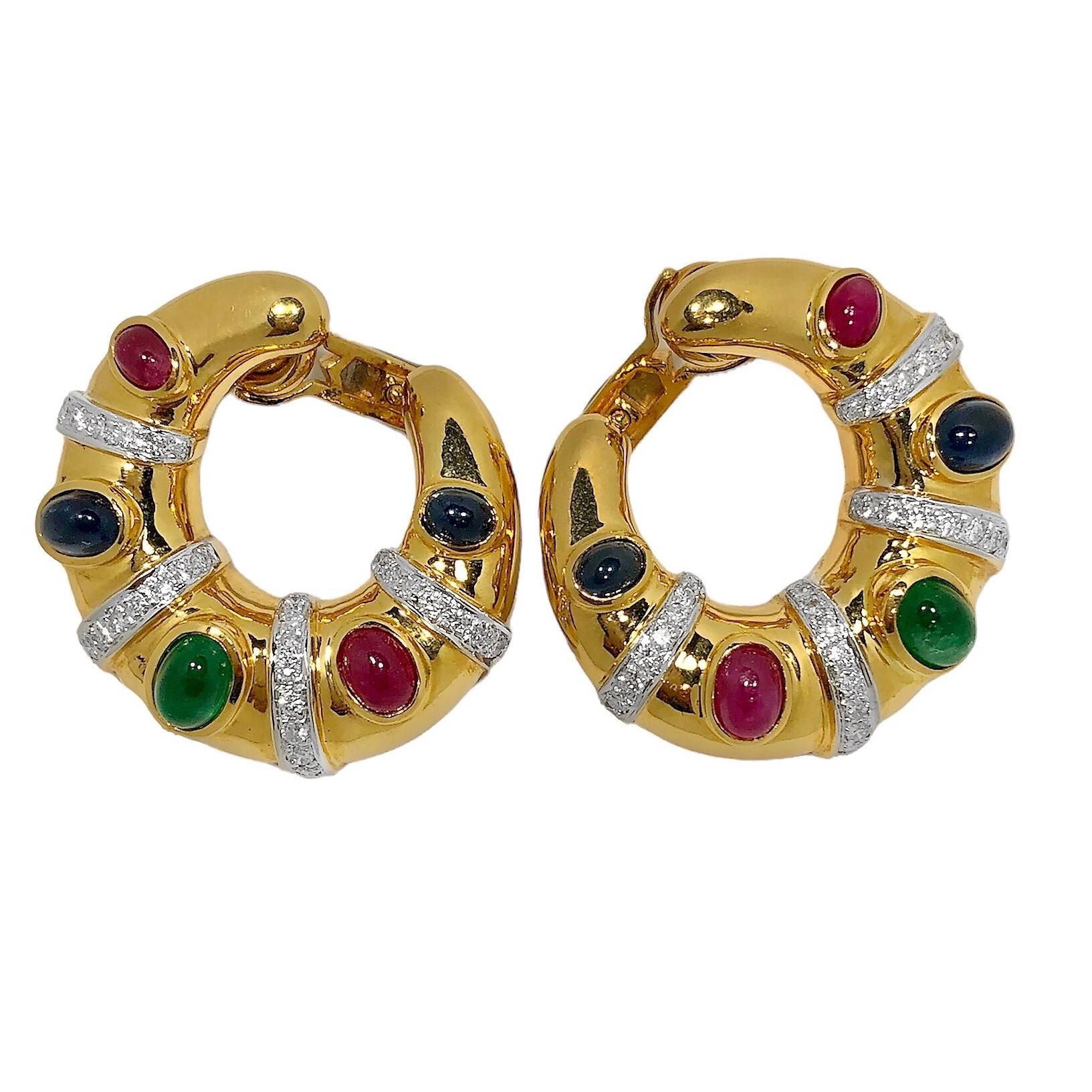 This eye catching pair of vintage 18k yellow gold hoops are each bezel set with five vibrant cabochon stones; emeralds, rubies and sapphires, that
are separated by rhodium strips of brilliant cut diamonds. Total approximate precious stone weight is