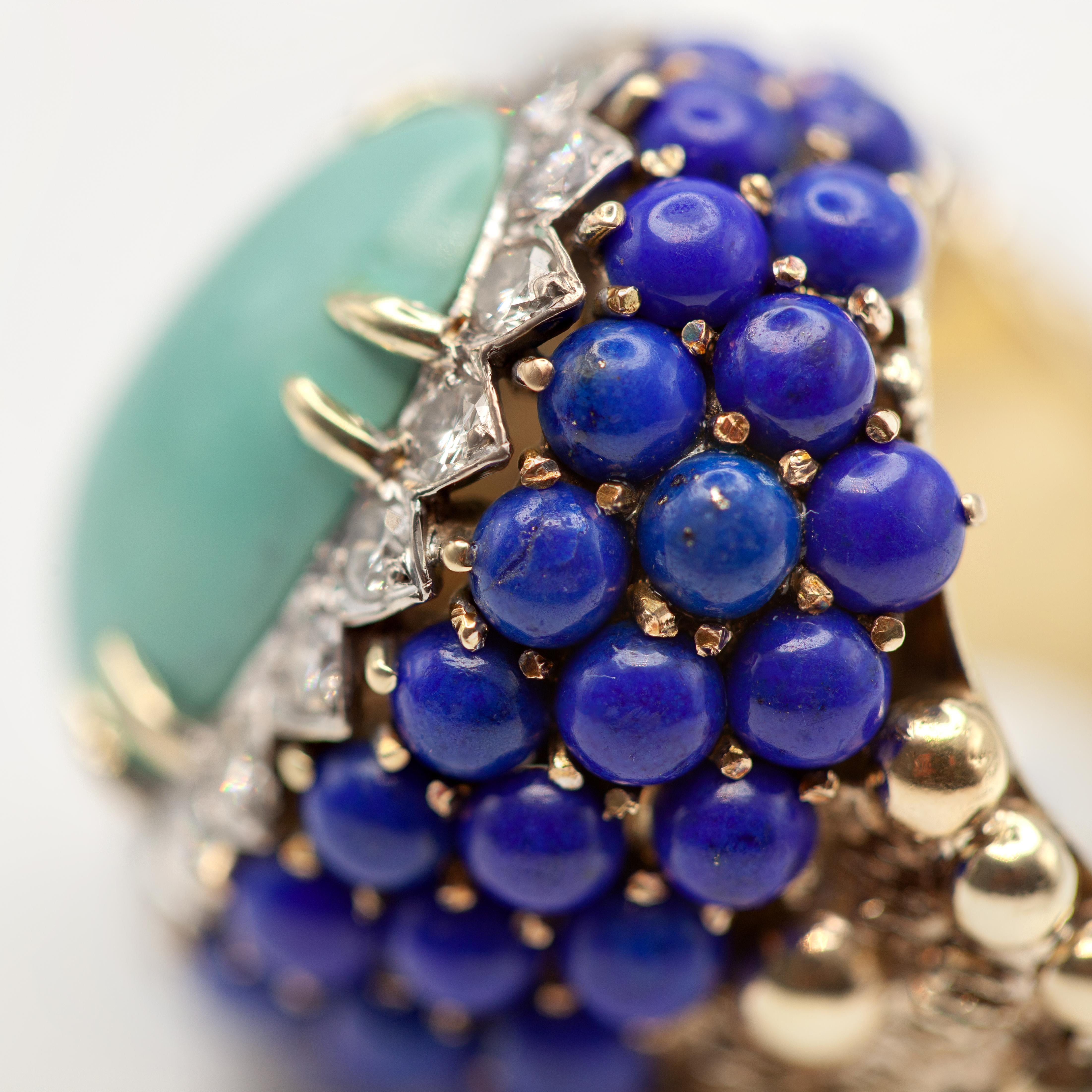 Cette magnifique bague de cocktail en turquoise lapis-lazuli est réalisée en or jaune 14 carats. La pièce centrale présente une grande turquoise cabochon d'environ 13,71 carats, sertie et entourée d'un halo de 18 diamants taille brillant d'environ