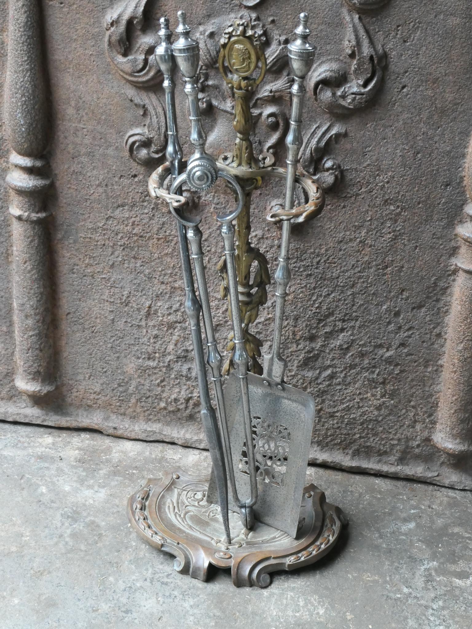 Beautifully decorated 18th - 19th century English Georgian fireplace tools. The tool set consists of tongs, shovel, poker and stand. The stand is made of brass while the tools are made of polished steel. The set is in a good condition and is fully