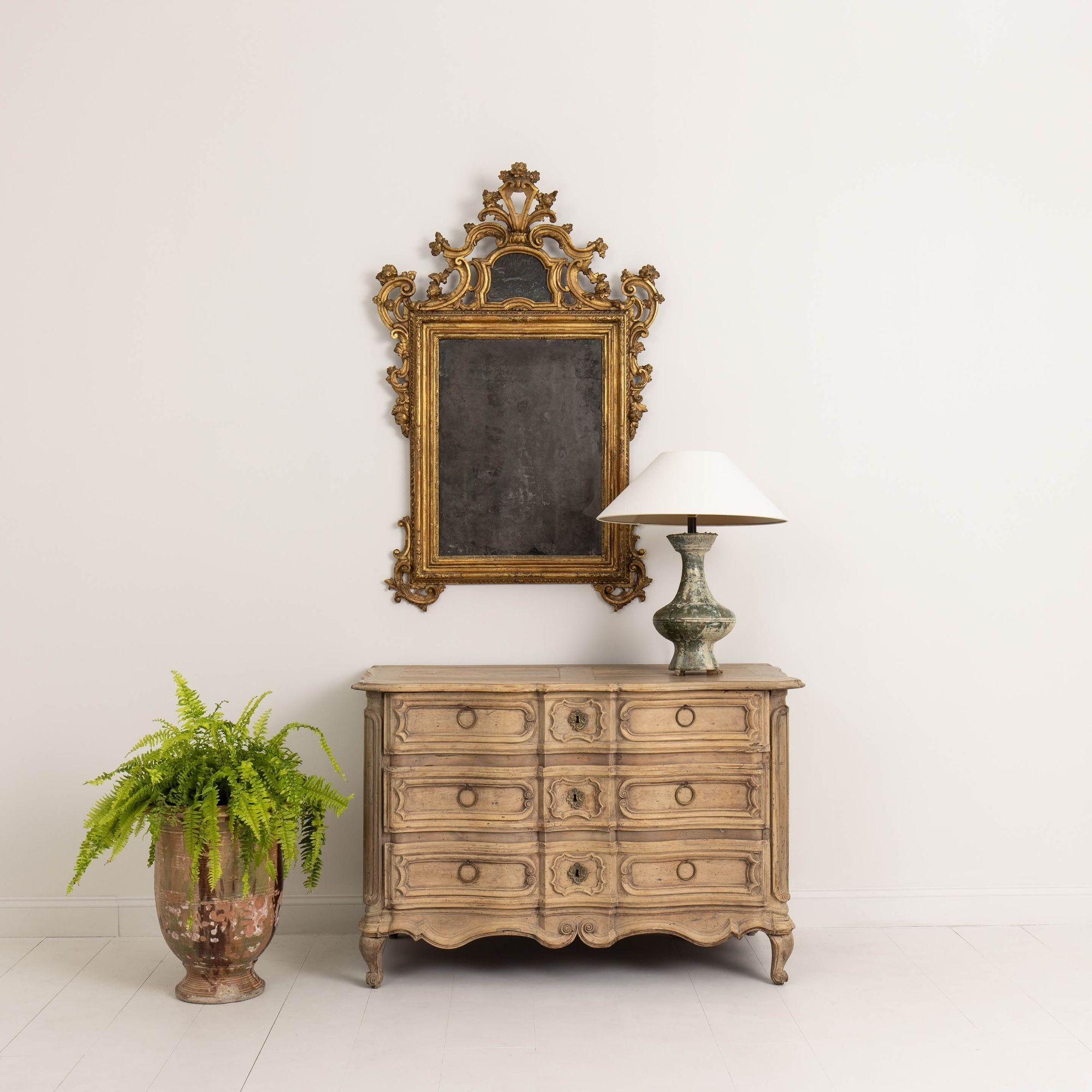 A large, antique chest of drawers with serpentine shape, circa 1770. This beautiful, hand-carved, bleached walnut commode has a shaped top, shaped recessed panel drawers, intricately carved side panels, scalloped apron and is raised upon short,