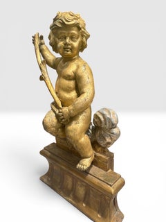 Grande statuetta italiana in legno intagliato, dorato e argentato, raffigurante un putto seduto, in stile barocco del XVIII secolo.