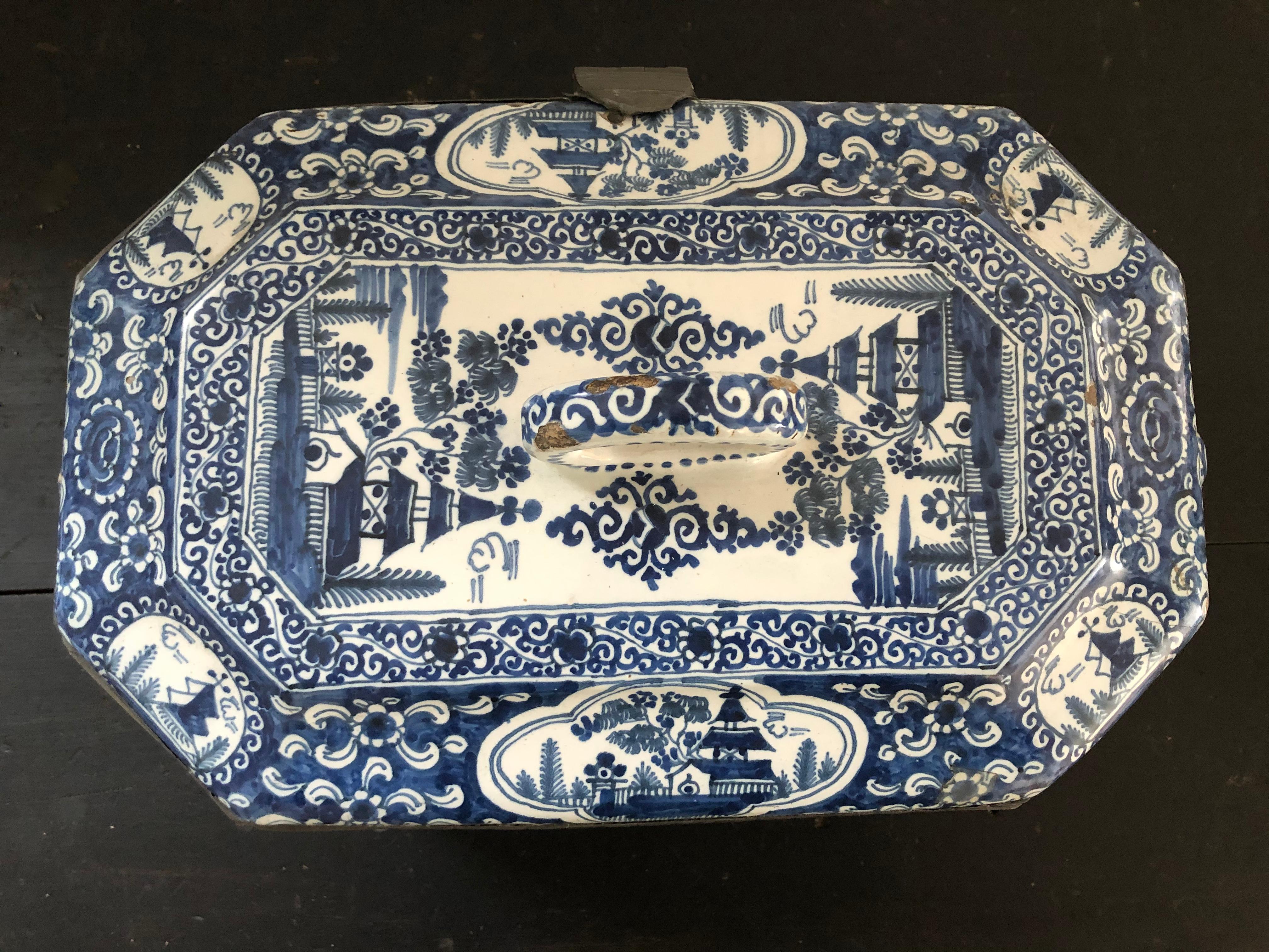 A generously proportioned 18th century hand painted blue and white Delft pottery box, of rectangular form with cut corners, the two ends with circular strap handles, the domed top with loop strap handle. The edges of the box where the top and bottom