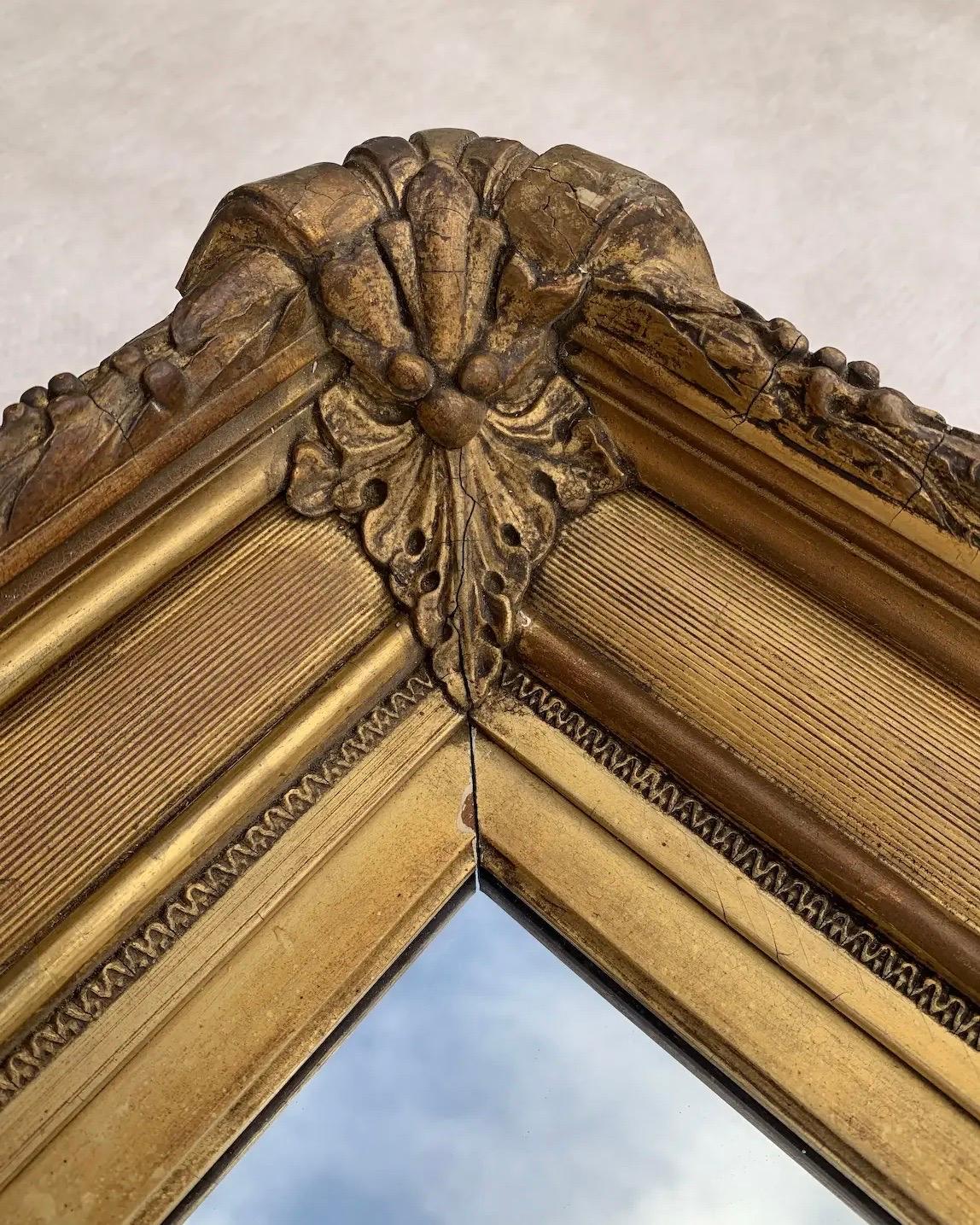 Offering a large ornately carved Italian wall mirror featuring an antique giltwood frame from the late 18th century. At nearly 42”L x 34”W with a substantial 3-1/2” depth this piece is prepared to make an elegant statement. Perfect companion for a