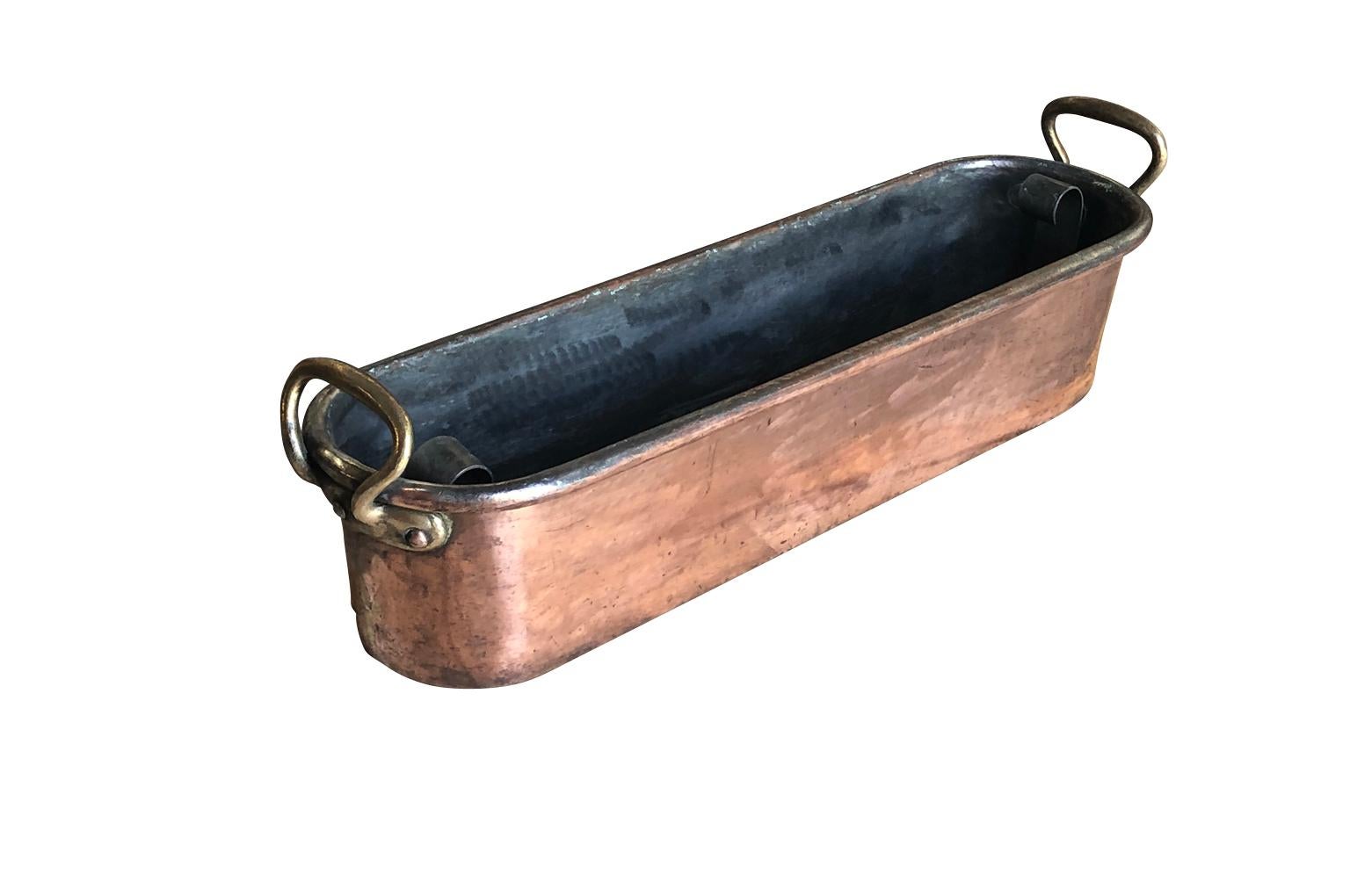 A large 18th century fish pan in copper from the South of France. The pan retains its original poaching tray. Five wholes have been punched into the bottom of the pan.  Wonderful quality. A great addition to a copperware collection.