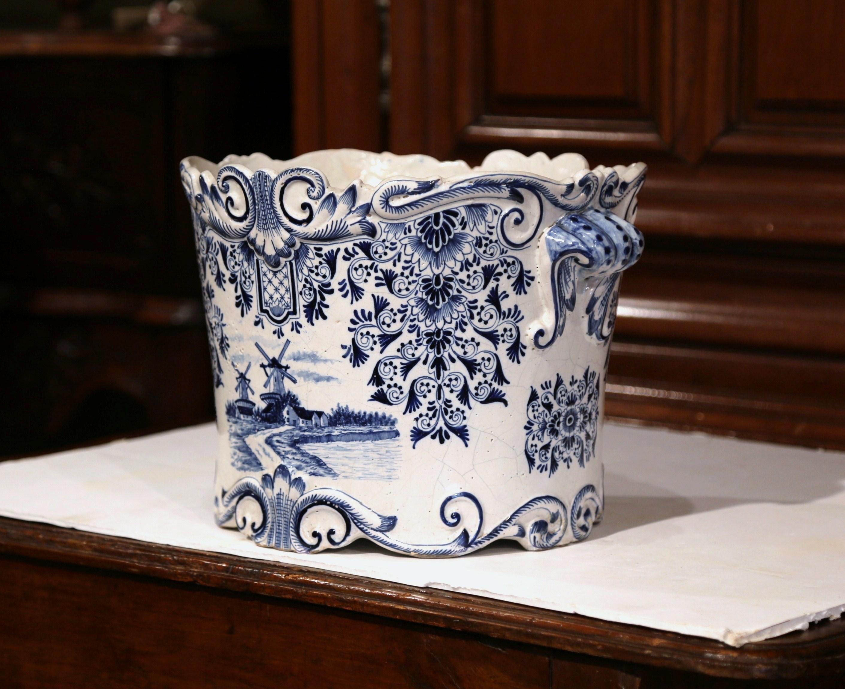 This large, antique faience planter was created in France, circa 1780. Round in shape, the blue and white cachepot is bevelled on the mouth, and is hand-painted on both sides. The motifs include carved shell handles on the sides, and traditional