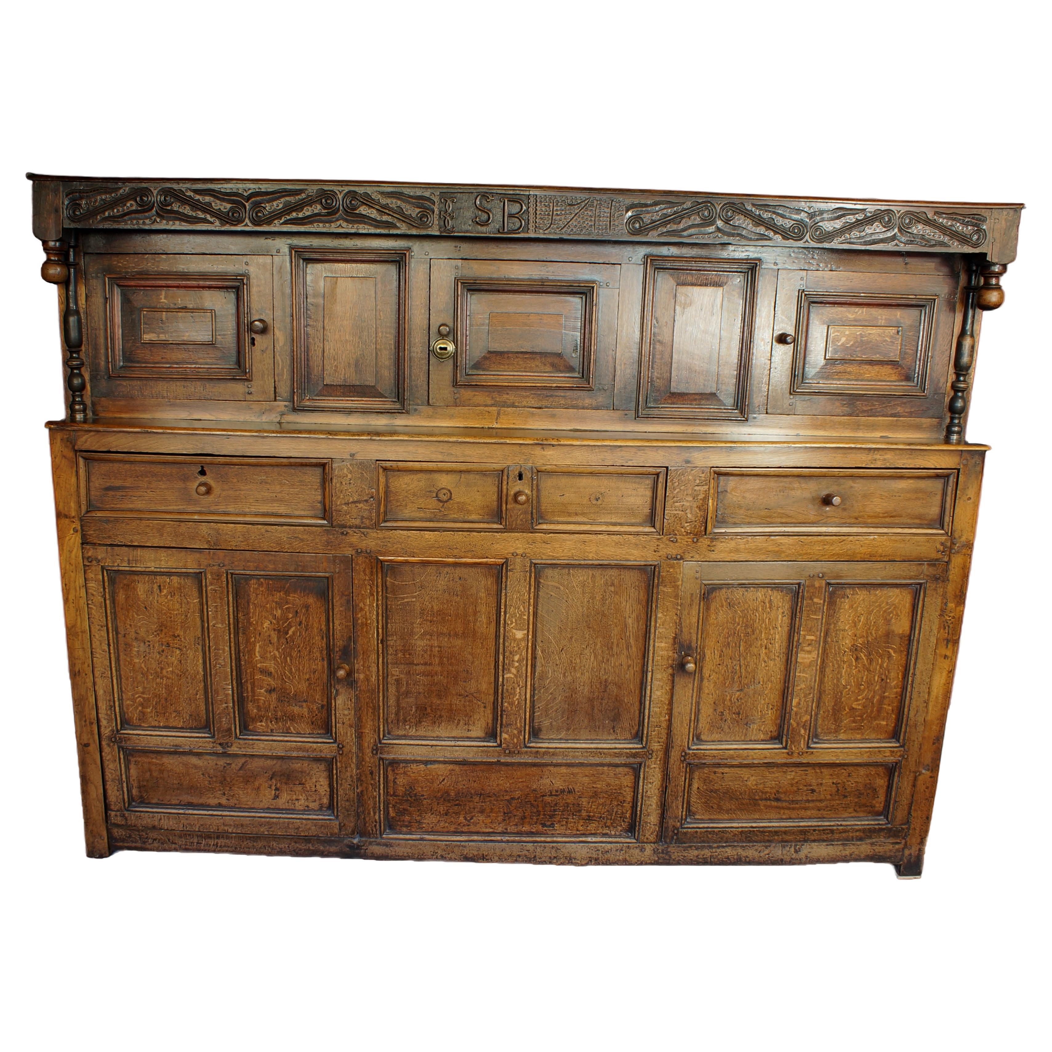 A Superb early 18th Century  Westmorland Oak Court Cupboard.
Having a carved top rail carved with the initials  I/J S B and dated 1711.
The upper section has three doors with raised fielded panels and two blind panels, above three moulded drawers