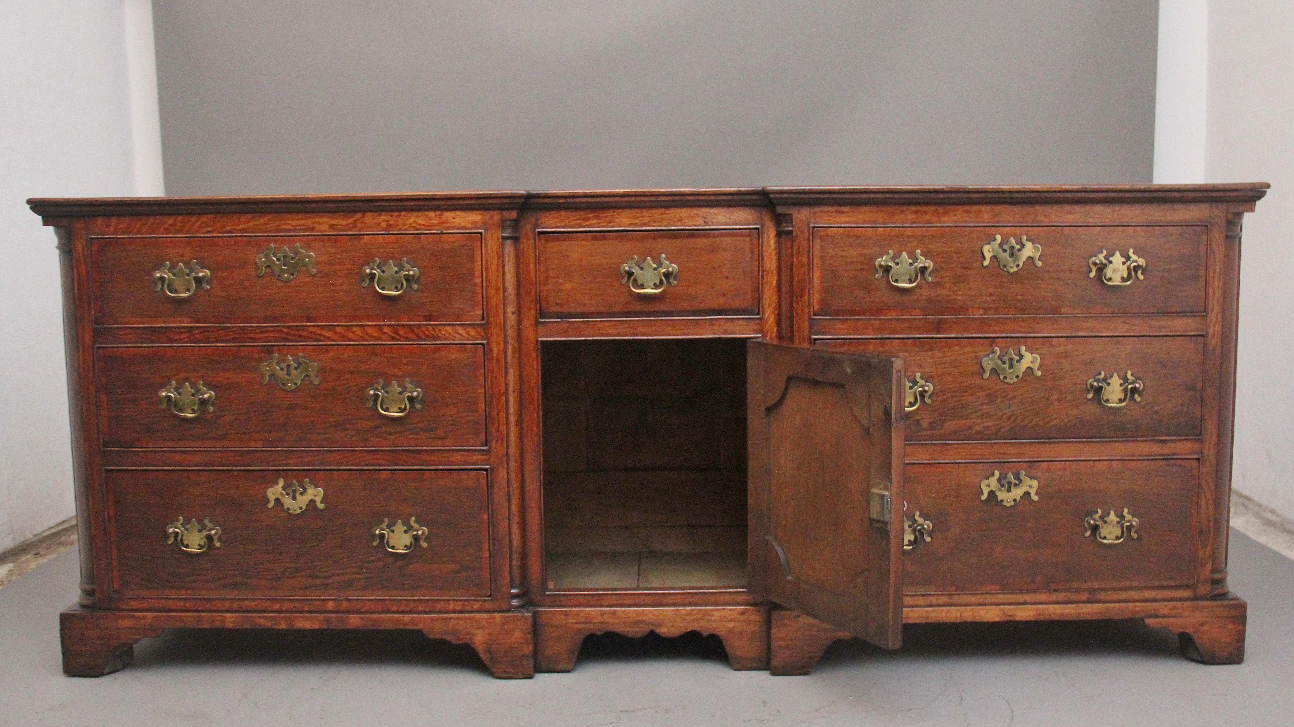 Un grande comò in rovere del XVIII secolo con un bel piano figurato sopra una combinazione di sei grandi cassetti graduati con fasce incrociate sui frontali dei cassetti, tre per ogni lato, con maniglie e rosette in ottone, un'anta centrale