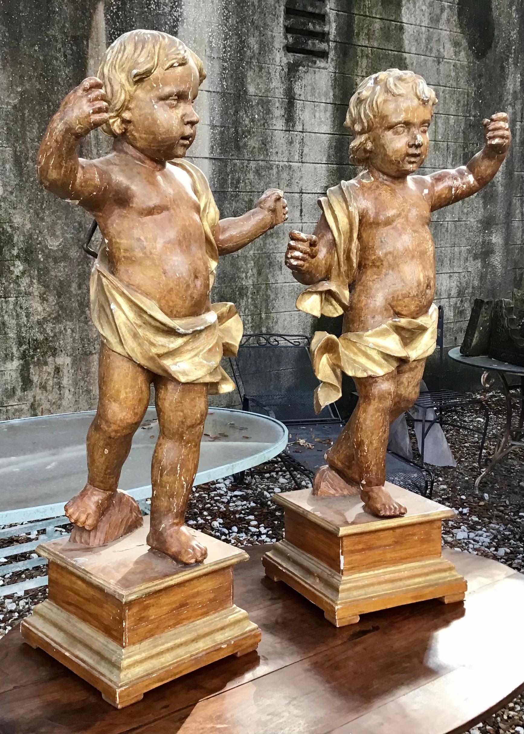 This pair of Italian standing cherub carvings from the 18th century. Standing at almost 4 feet tall, the pair are quite large and realistic. Very impressive. With original hand forged iron hooks to secure them to a wall. An impressive pair in what