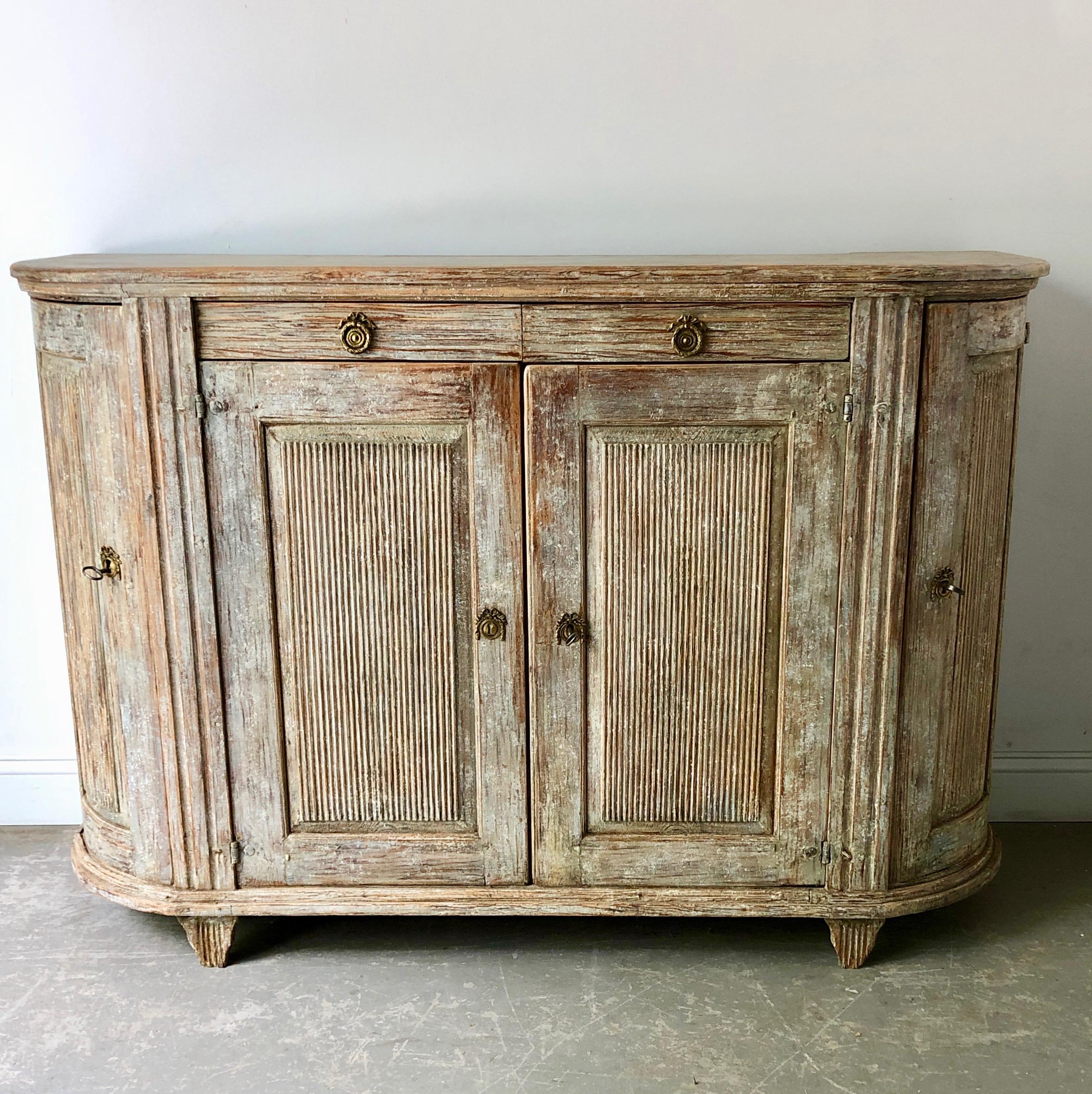 Very large, 18th century Swedish period Gustavian sideboard in classic Gustavian manor; rounded form with reeded corner posts, four paneled reeded doors and two drawers for storage, all resting on short reeded tapered feet. Wonderful find with a lot