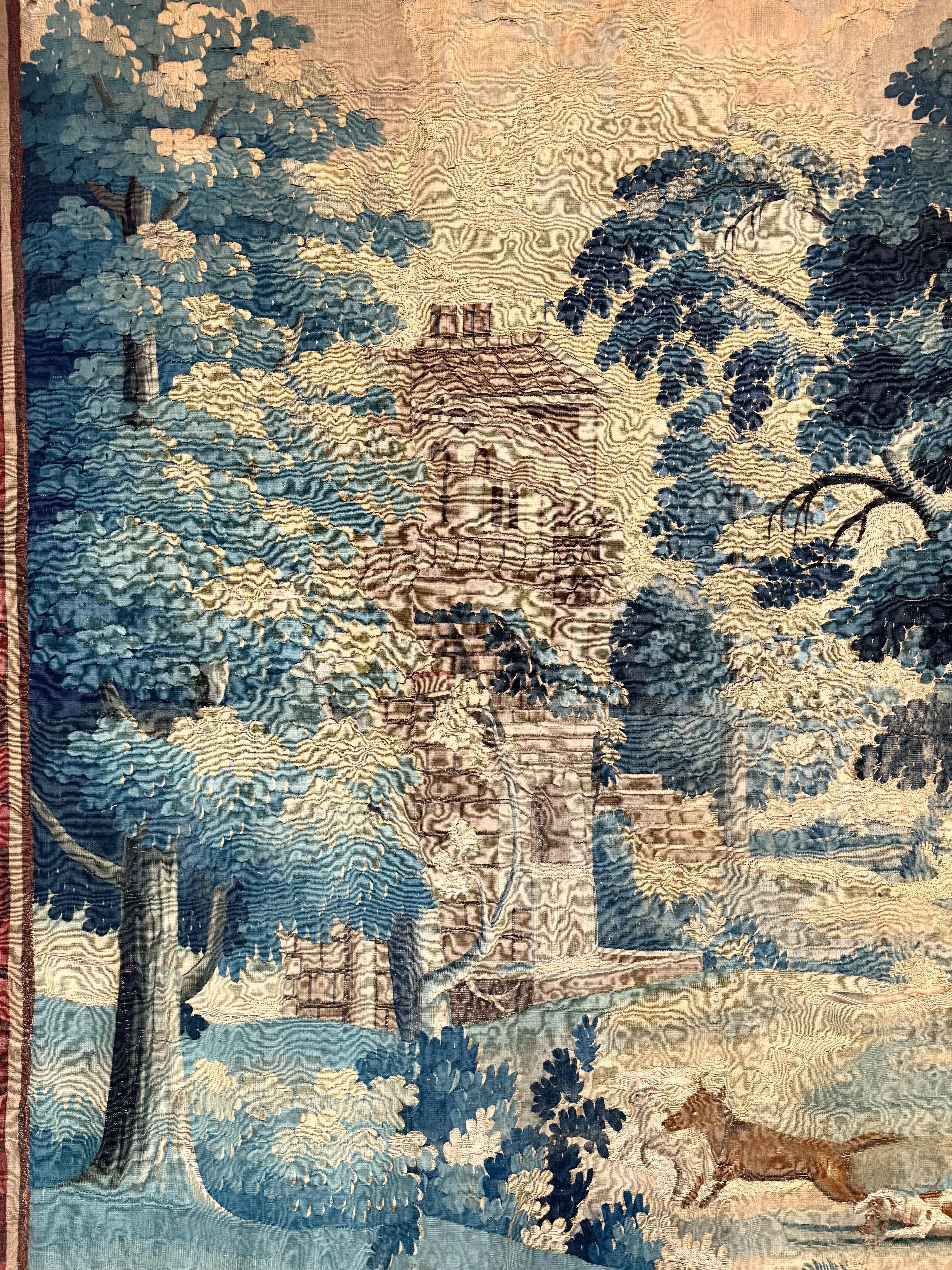 Cette grande tapisserie de verdure du XVIIIe siècle est un exemple frappant de l'art et de la narration que l'on trouve dans le tissage européen. Tissé en laine et en soie, il représente un paysage pastoral composé de grands arbres feuillus, de