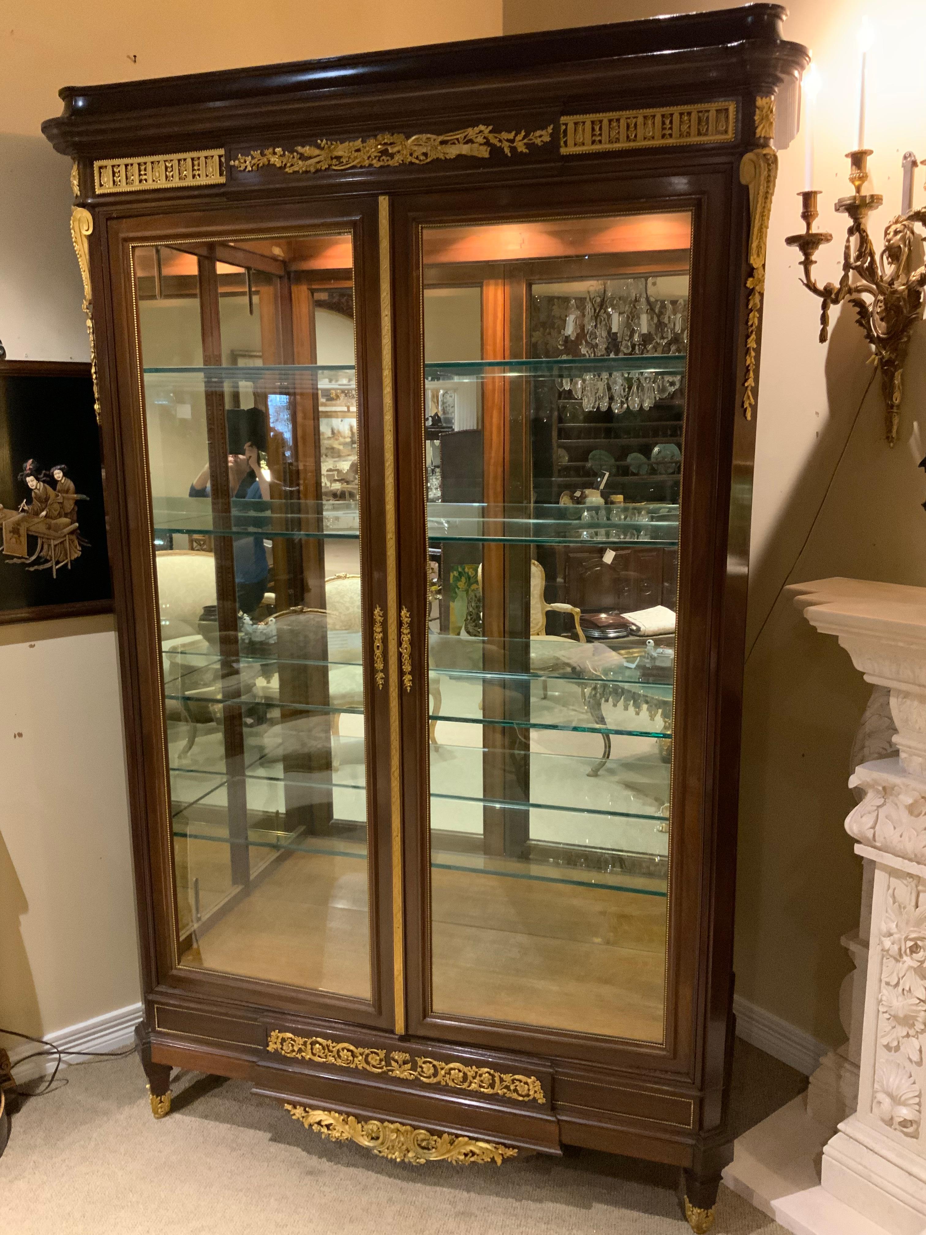 Exceptional quality Louis XVI -Style display cabinet having four glass shelves. Mahogany 
With marquetry inlay on the sides. Bronze dore mounts of a torch and quiver at the crest.
We’ll cast bronze dore mounts at the corners, bottom ant sabots on