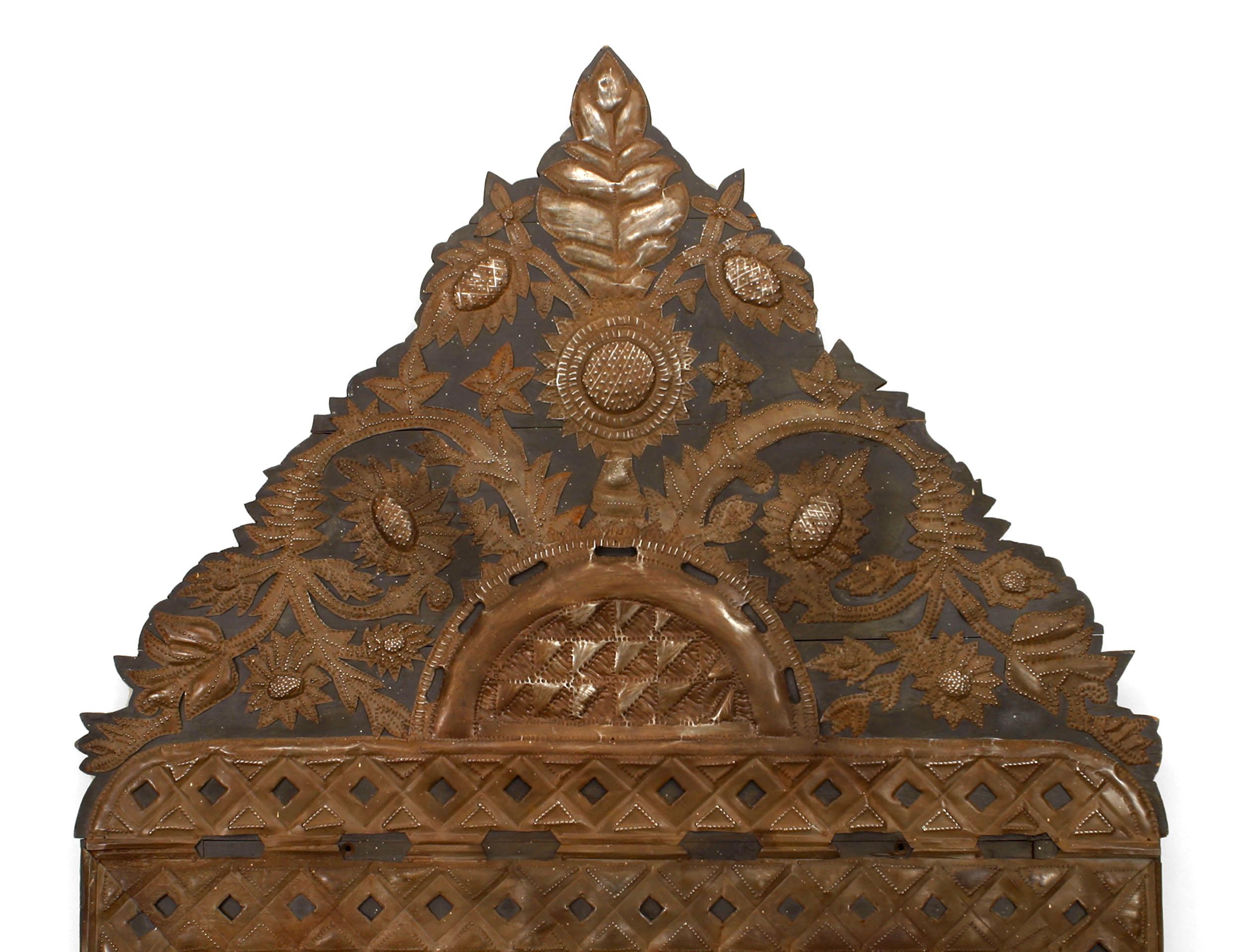 Specchio da parete messicano (anni '20) in metallo stampato con cornice in legno ebanizzato, bordo con disegno a reticolo e motivo a rondine con frontone.
  