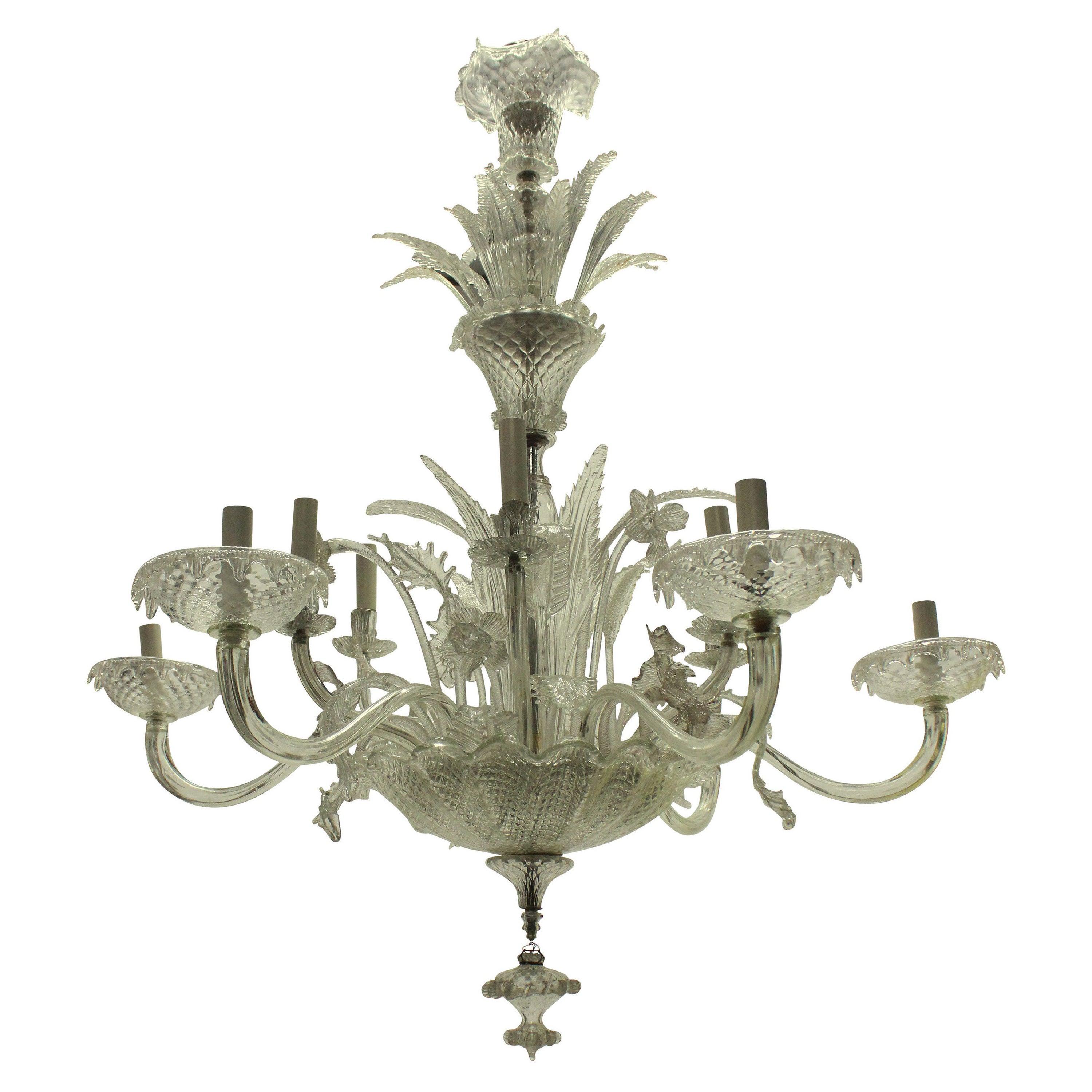 A large Italian murano glass chandelier of fine quality, with twelve arms, extending from a large patterned receiver dish with finial. The upper section profusely decorated with foliage and the central stem with a basket containing foliage and
