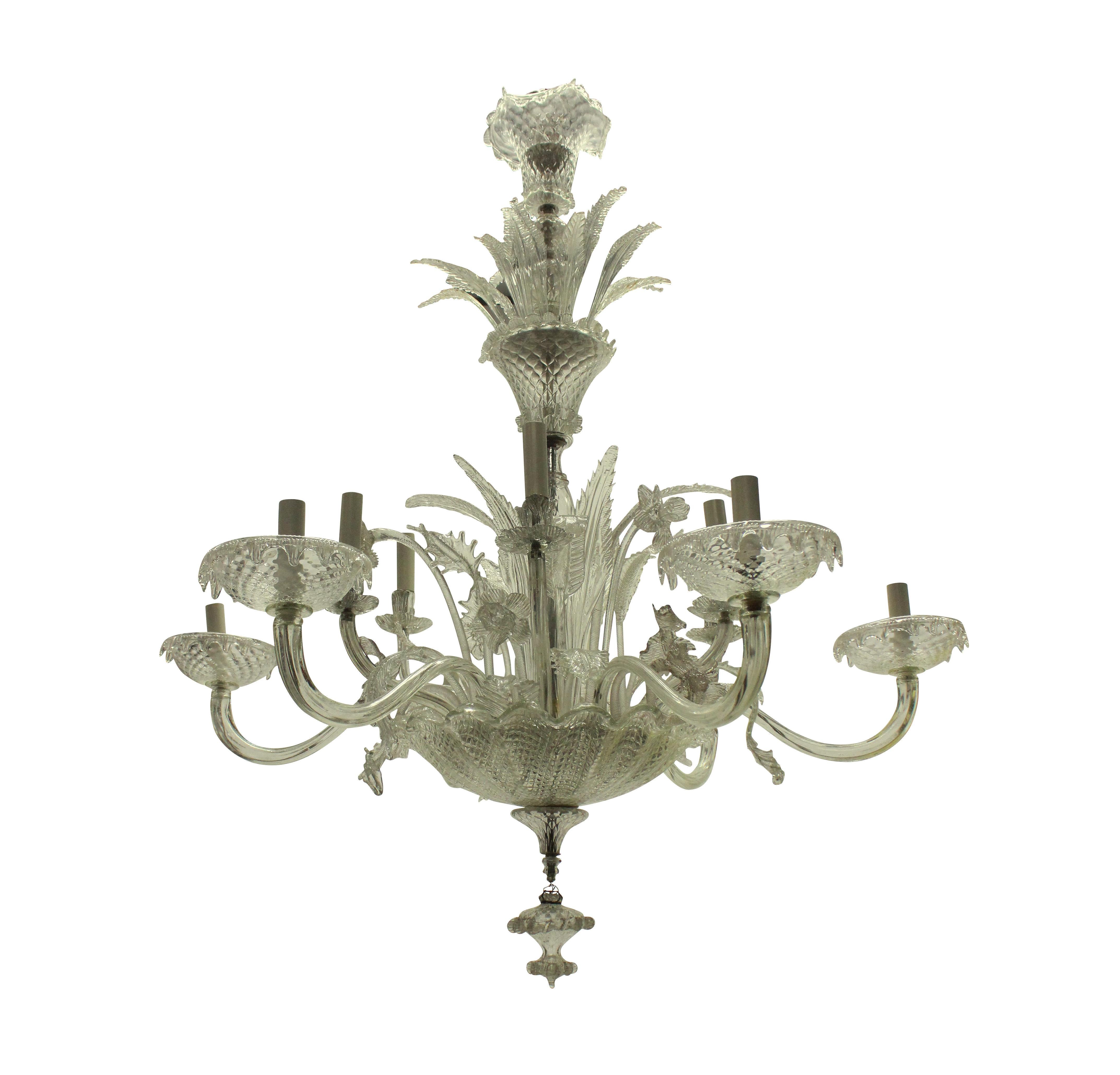 A large Italian Murano glass chandelier of fine quality, with twelve arms, extending from a large patterned receiver dish with finial. The upper section profusely decorated with foliage and the central stem with a basket containing foliage and