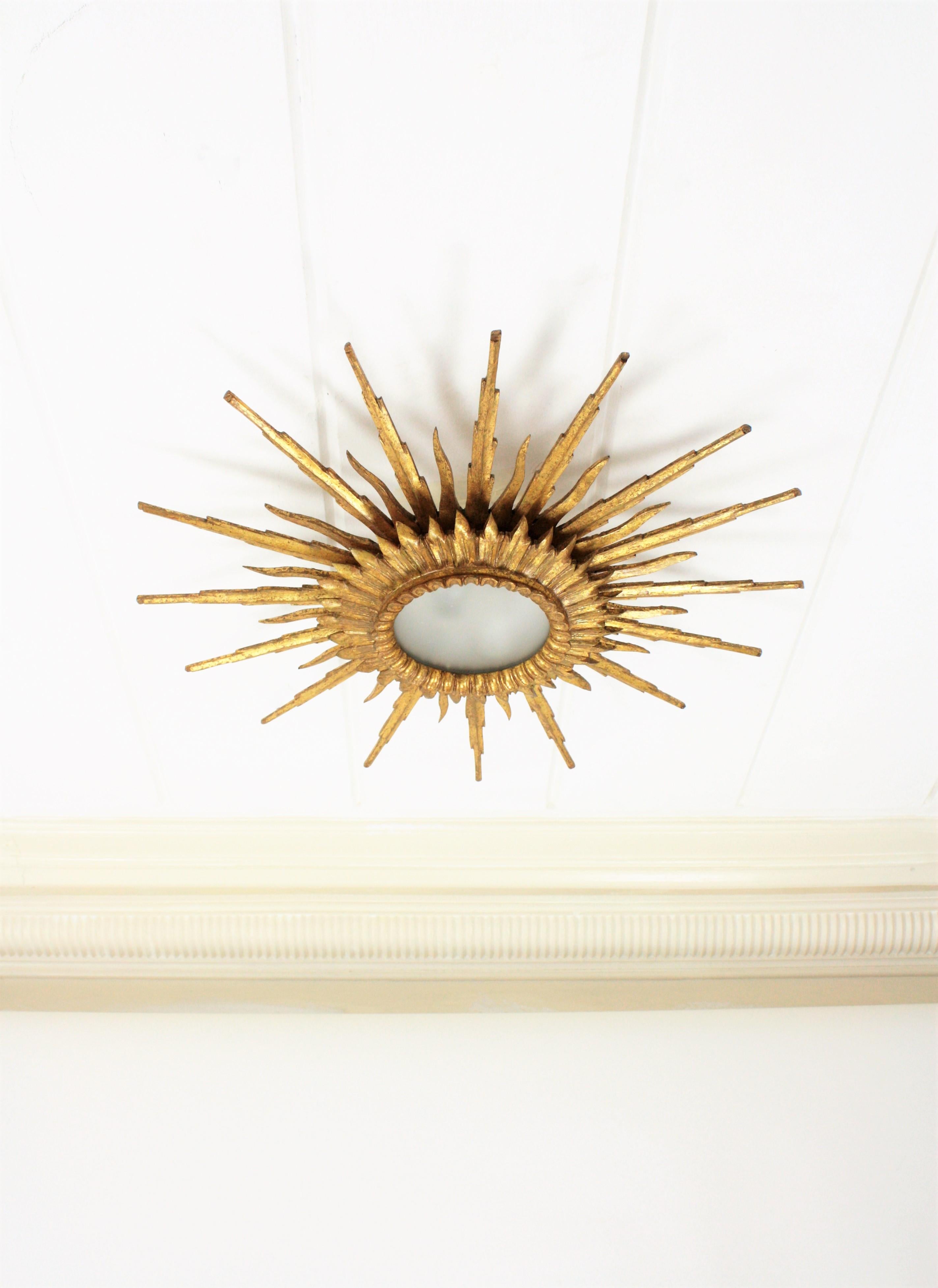 An spectacular gold leaf gilt sunburst flush mount or ceiling light fixture in Baroque style made in Spain at the mid-20th century. Large size with two layers of beams in different sizes that make this piece gorgeous and highly decorative even more