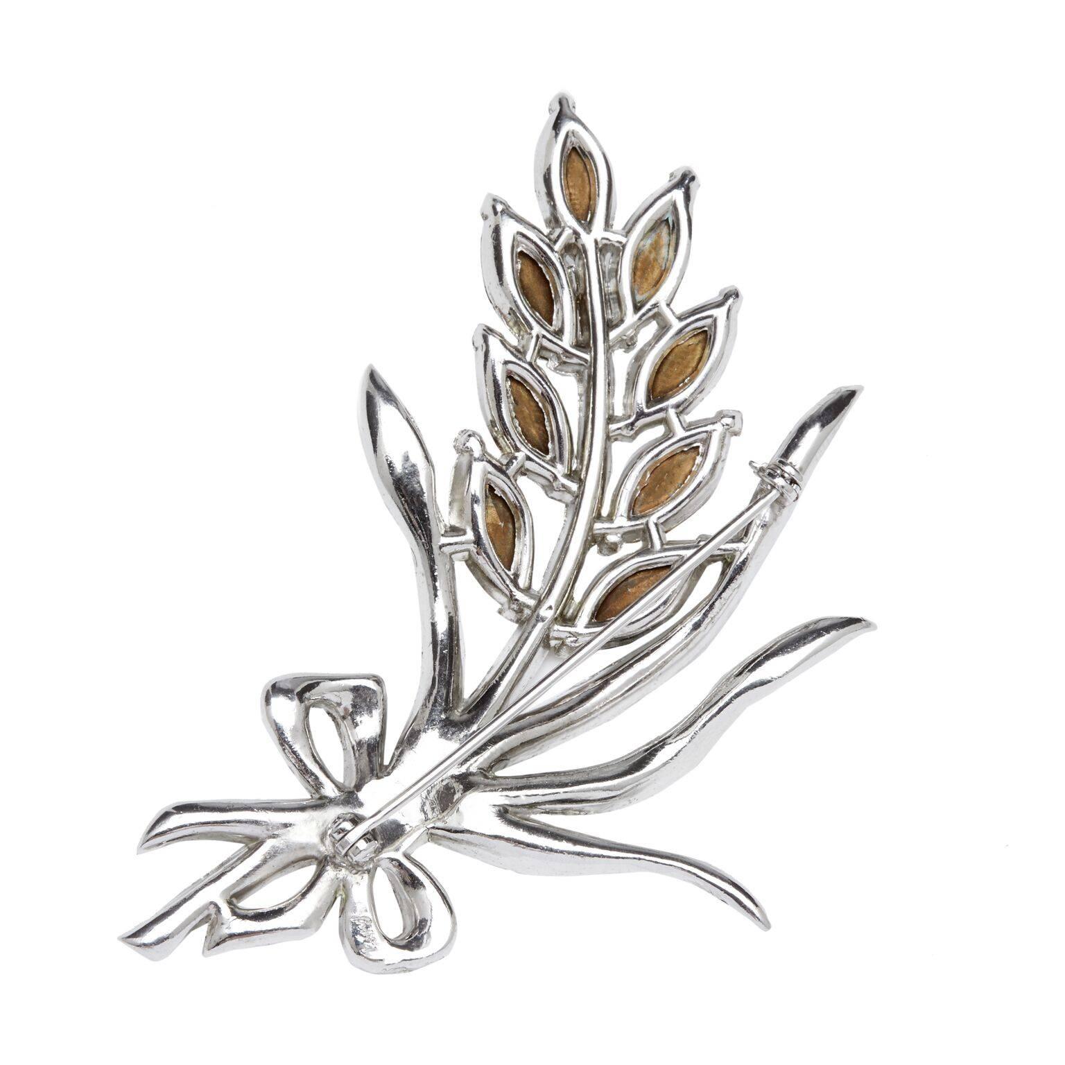 This exquisite 1940s rhodium plated flower spray broach with prong set rhinestones is manufactured by the high quality costume jewellery manufacturing giant Coro Inc.  Large marquise prong set rhinestones are arranged around a spray encrusted with