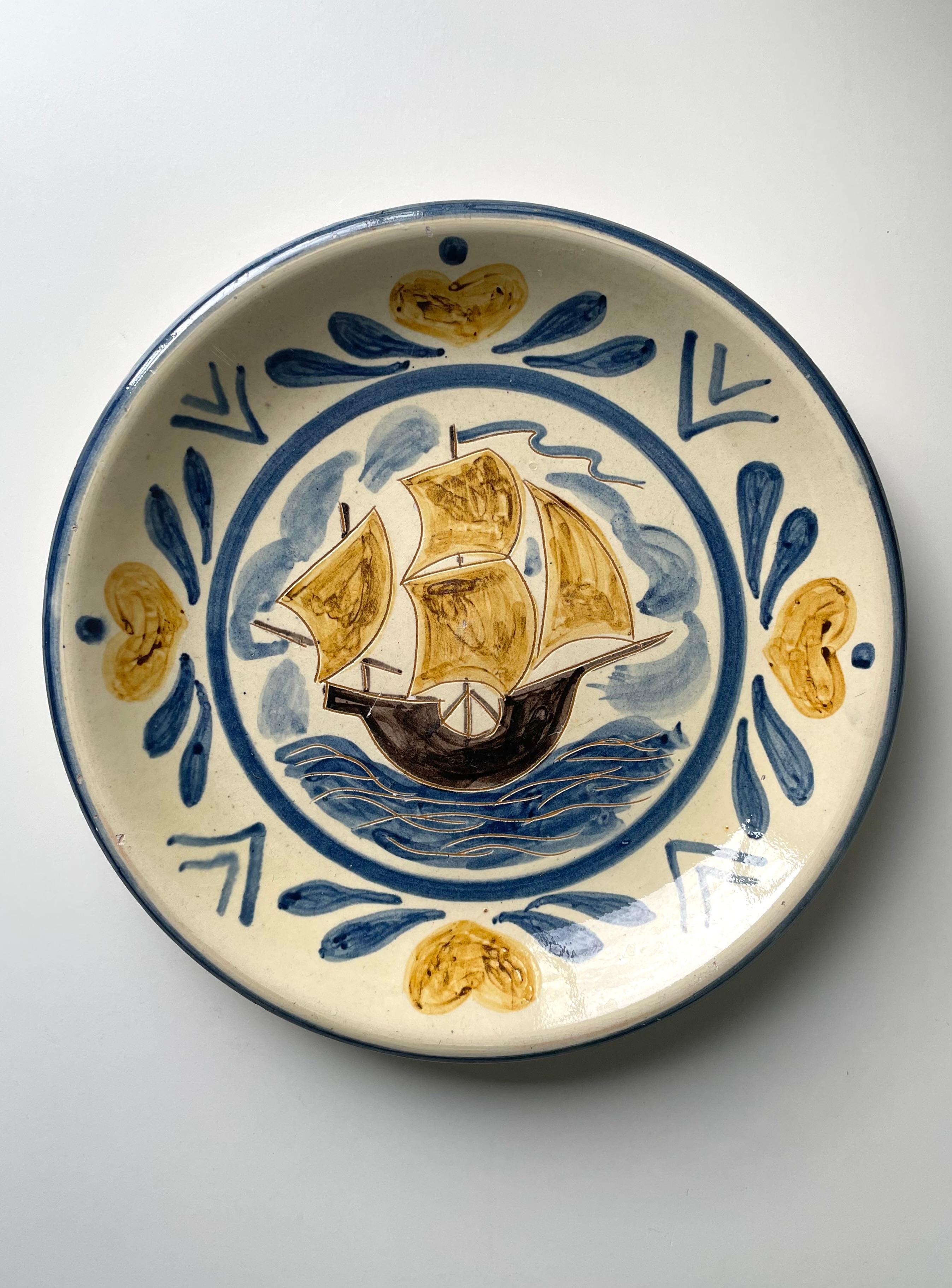 Large Danish early midcentury decorative centerpiece dish handmade in the 1940s at Humlebæk Keramik in the small town of Espergærde in northern Zealand. Cream yellow base with hand-painted dark brown ship with warm yellow sails on wavy blue seas and