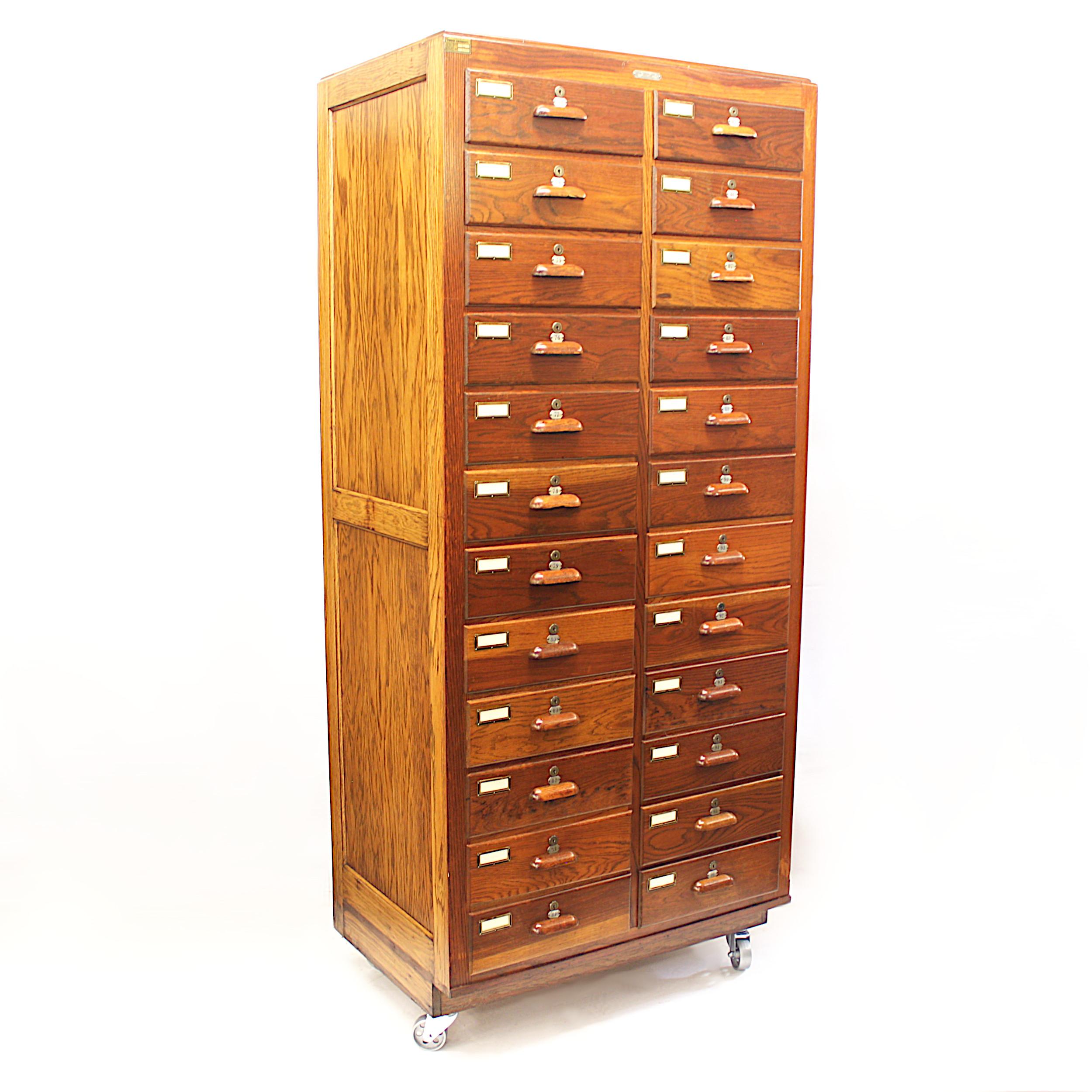 Wonderful vintage 1940s oak cabinet by the Walrus Manufacturing Co. Cabinet features:

- 24 dovetailed drawers with locks
- Solid oak construction
- Paneled sides
- Metal-tag numbered drawers
- Four steel wheel casters

With its impressive