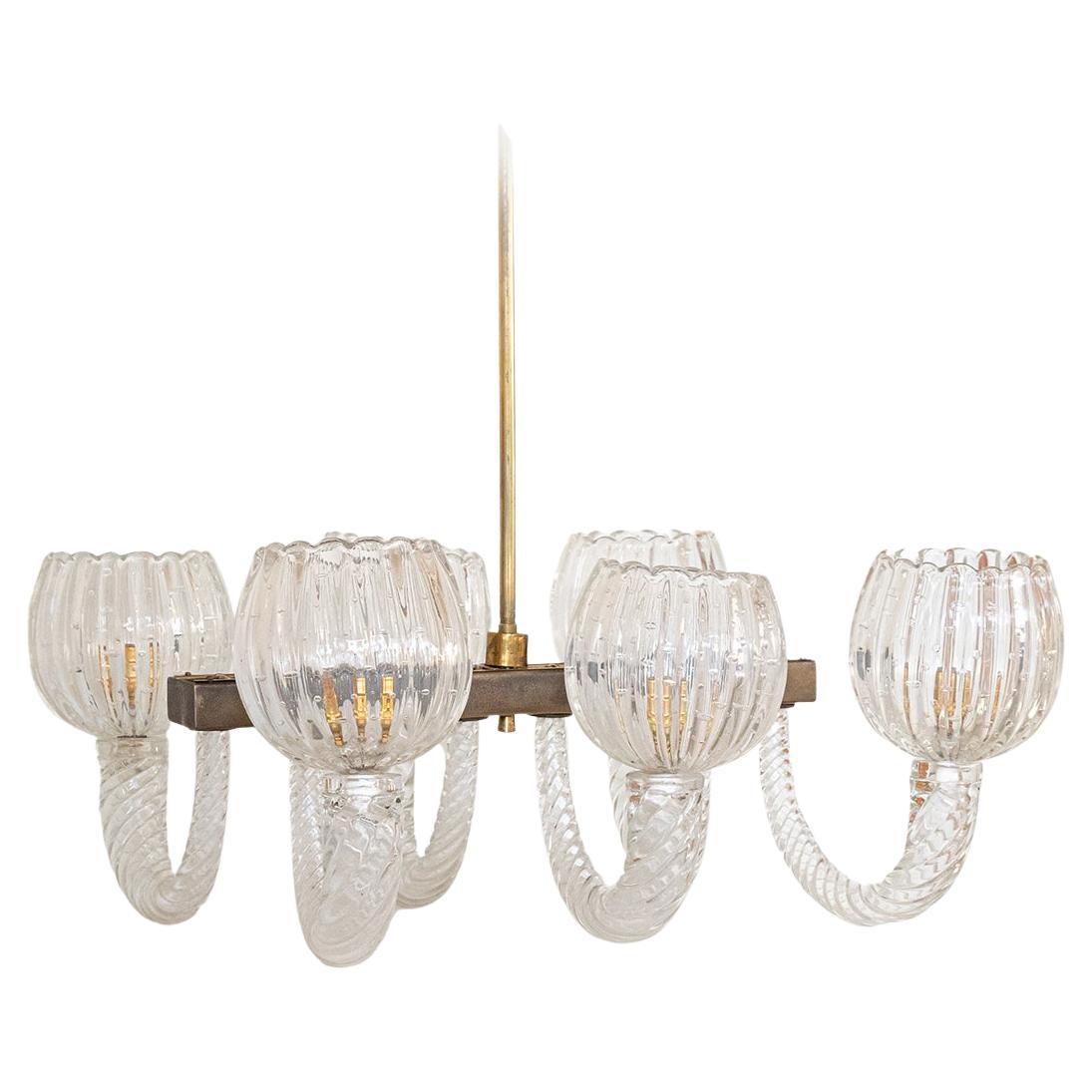 Impressive and large 1940's Barovier glass chandelier from Italy, 1940's. Six thick twisted glass arms arch out from an antiqued brass center, each holding a clear ribbed glass dome shade with scalloped lip. Beautiful clear bubbled glass is all