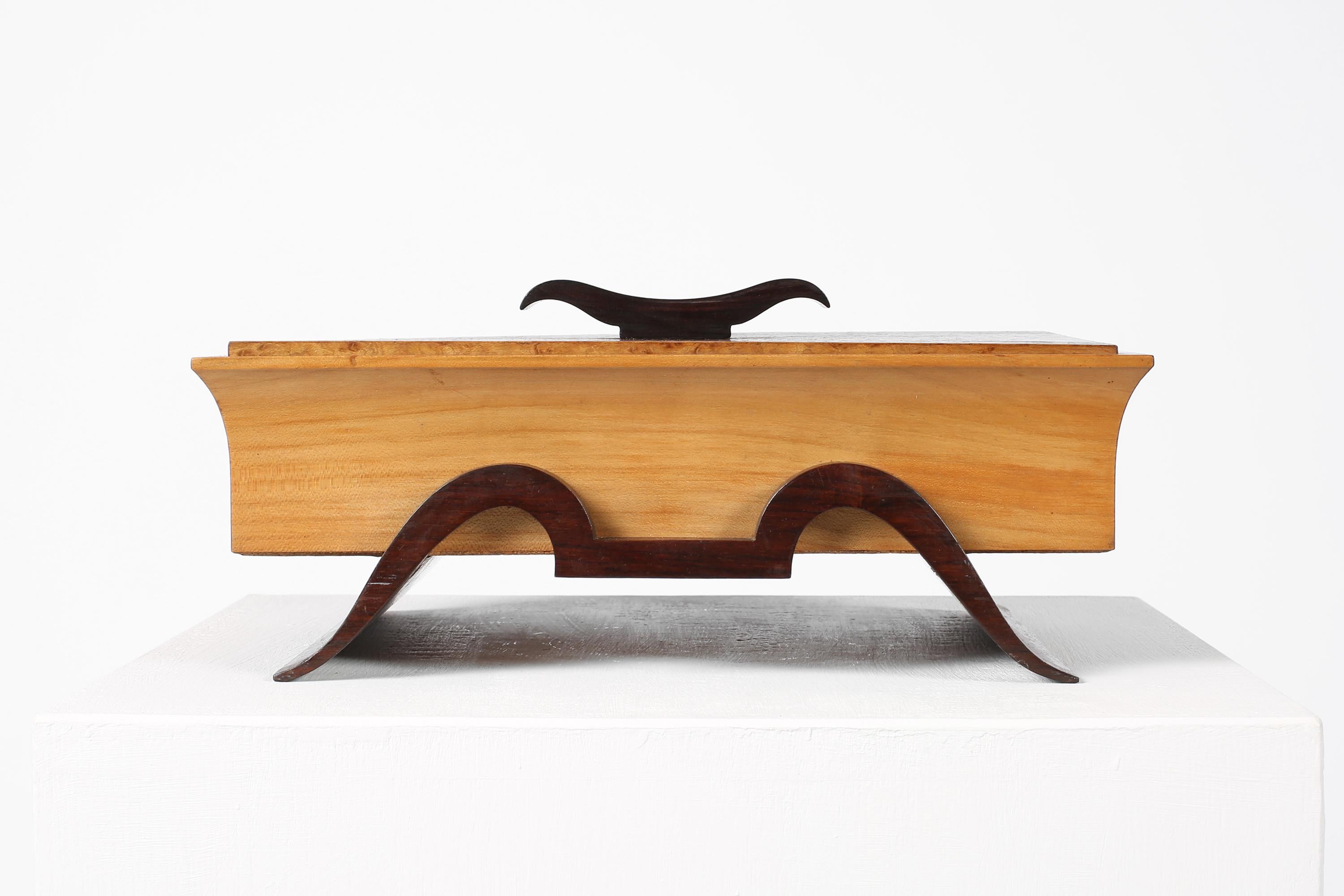 Una caja decorativa con tapa, asa y patas perfiladas. Construido con una mezcla de maderas nobles, como madera de satén, arce y palisandro. Forrado de terciopelo ciruela oscuro. Italiano, c. 1940.