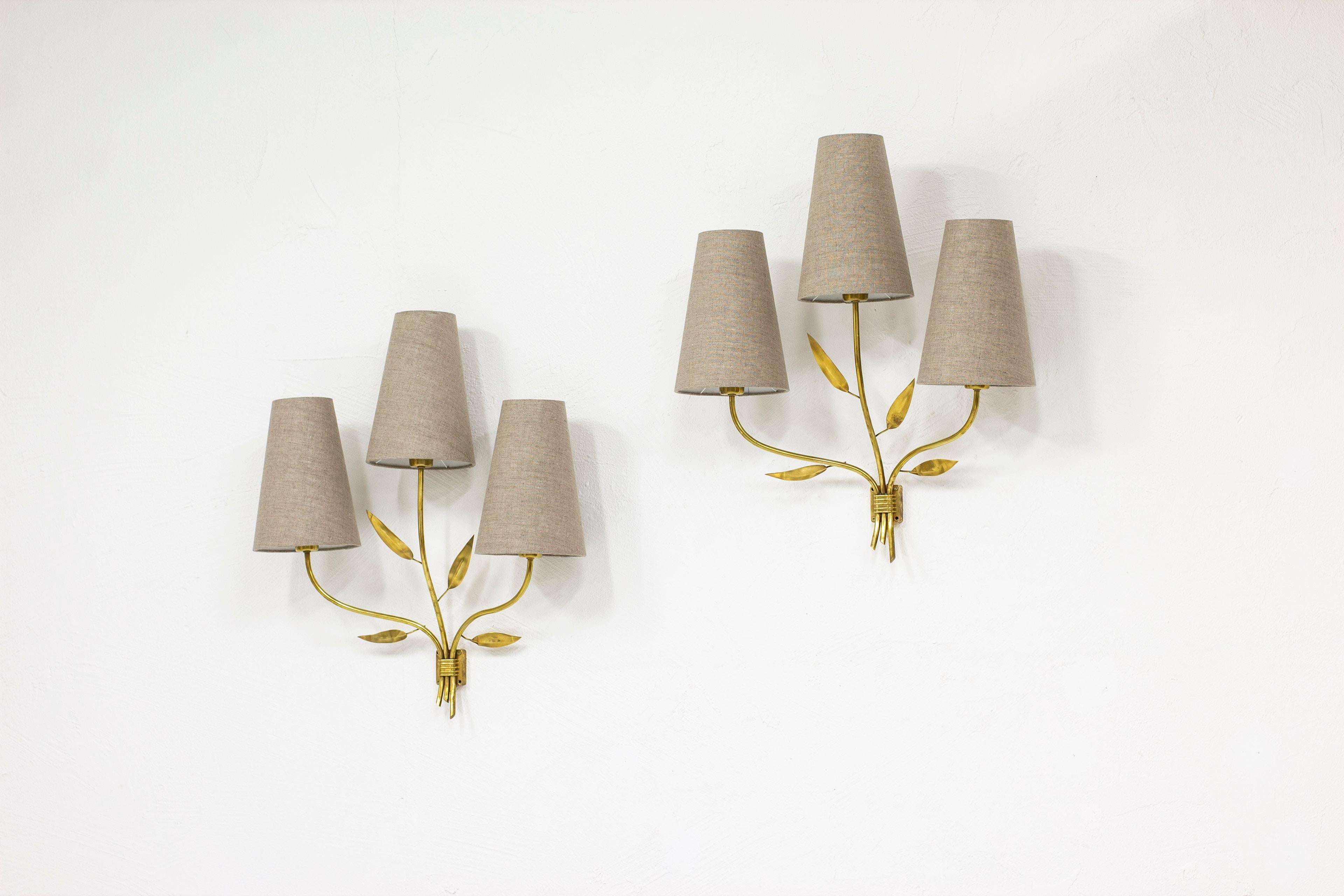 Pair of large Swedish modern wall lamps. Designed and Produced in Sweden during the 1940s. Three organic arms with stylized leaves in brass. Most likely made on commission. New lamps shades in natural/grey linnen fabric. can be adjusted for either