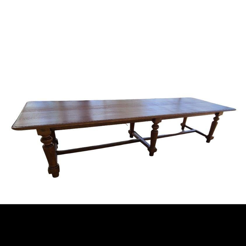 French farmhouse trestle dining table crafted from bleached oak. The table features a large trestle base with thick, chunky baroque style barley twist legs ending with shoe feet. The base is topped with a nearly 2-inch thick plank top that showcases