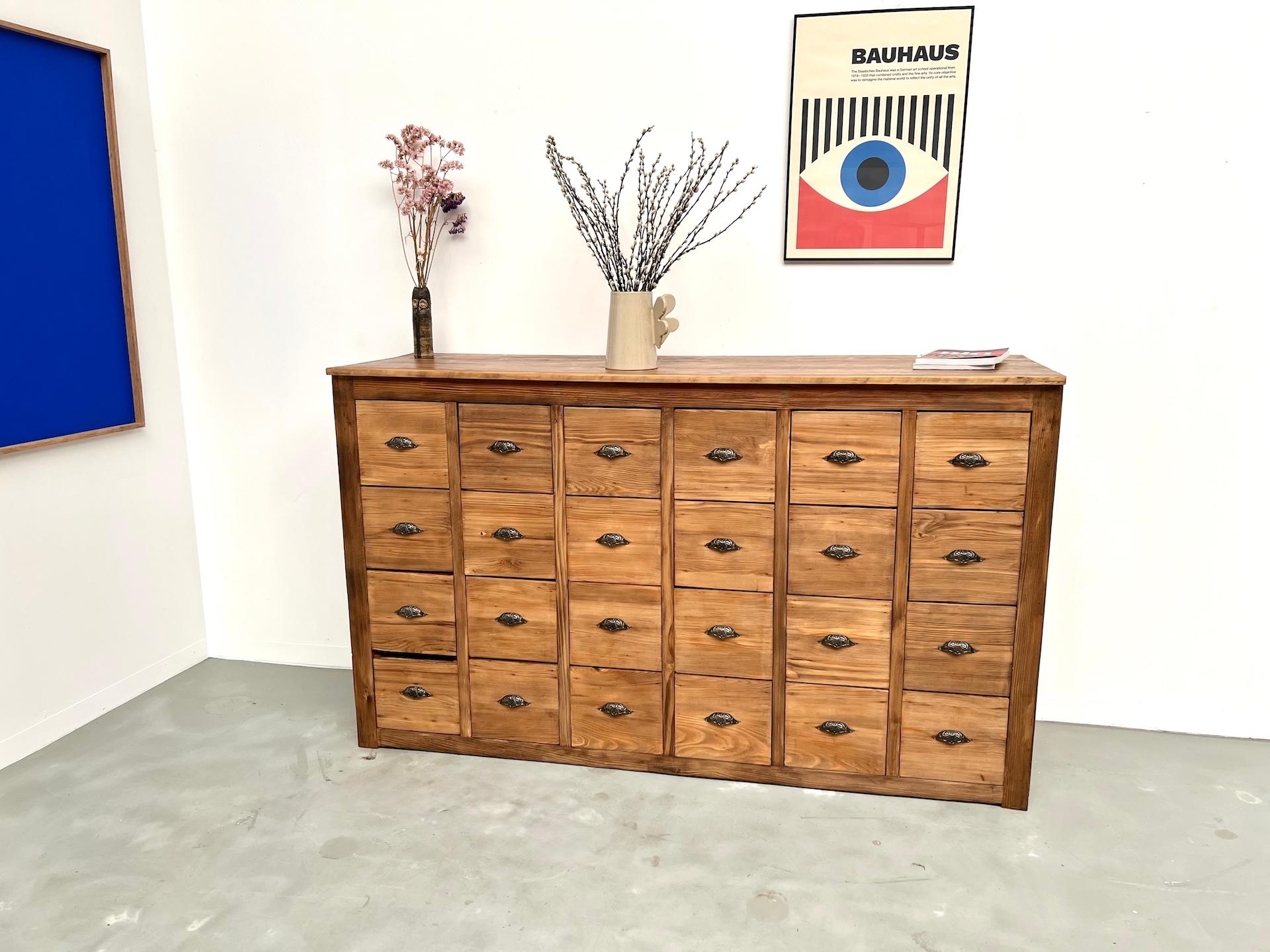 La Maison Lecan presenta questo spettacolare armadio a 24 cassetti degli anni '50, realizzato in pino massiccio. Completamente restaurato nel nostro laboratorio, combina l'eleganza funzionale dell'artigianato di metà secolo con l'autenticità grezza